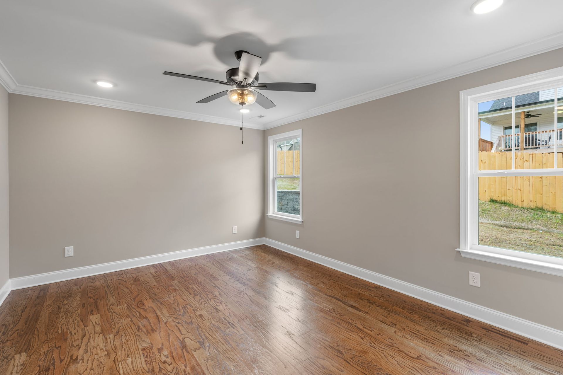 An empty living room with hardwood floors and a ceiling fan.