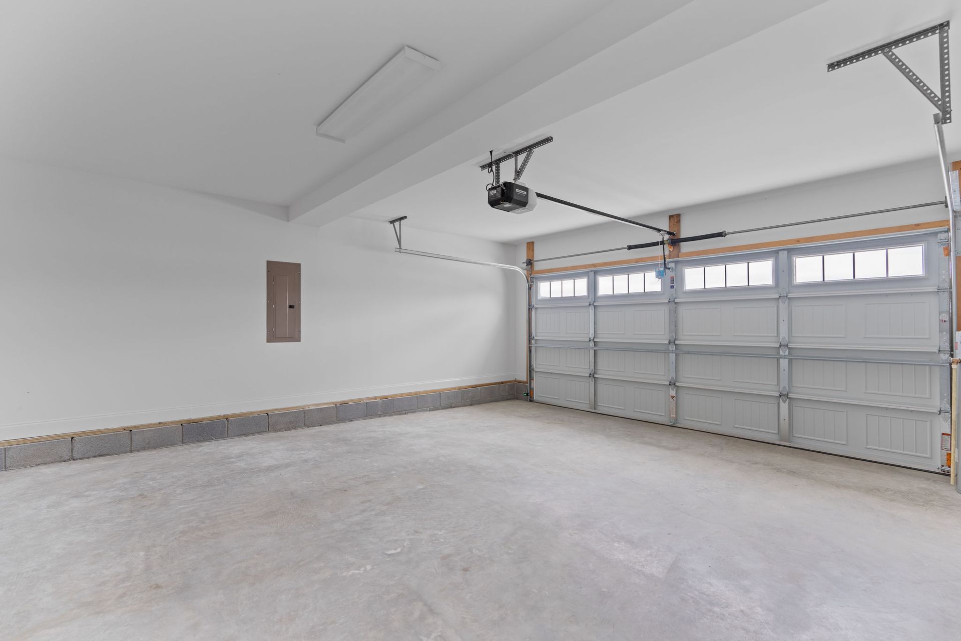 An empty garage with a garage door open and a ceiling fan.