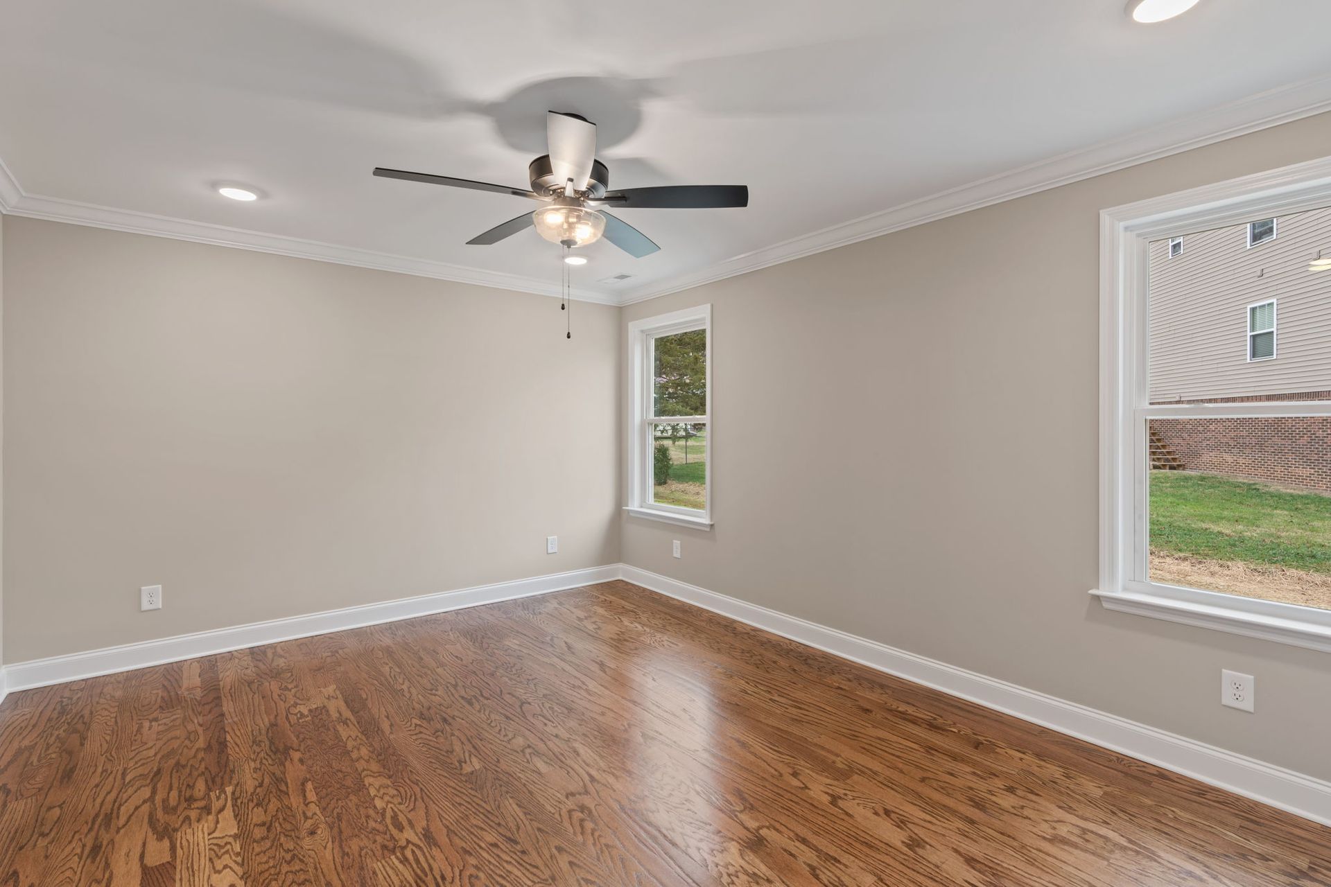 An empty living room with hardwood floors and a ceiling fan.