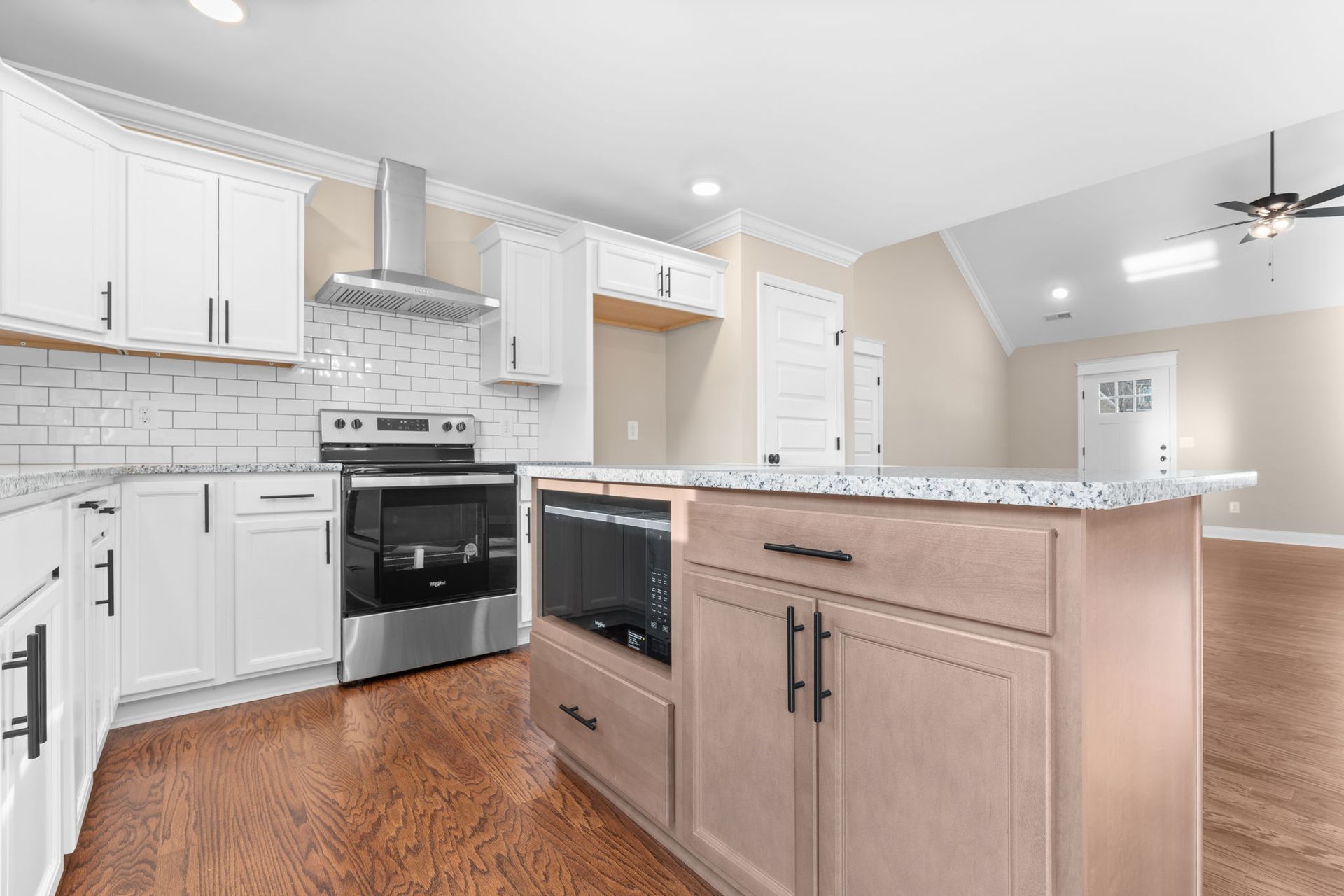 A kitchen with white cabinets , stainless steel appliances , and a large island.