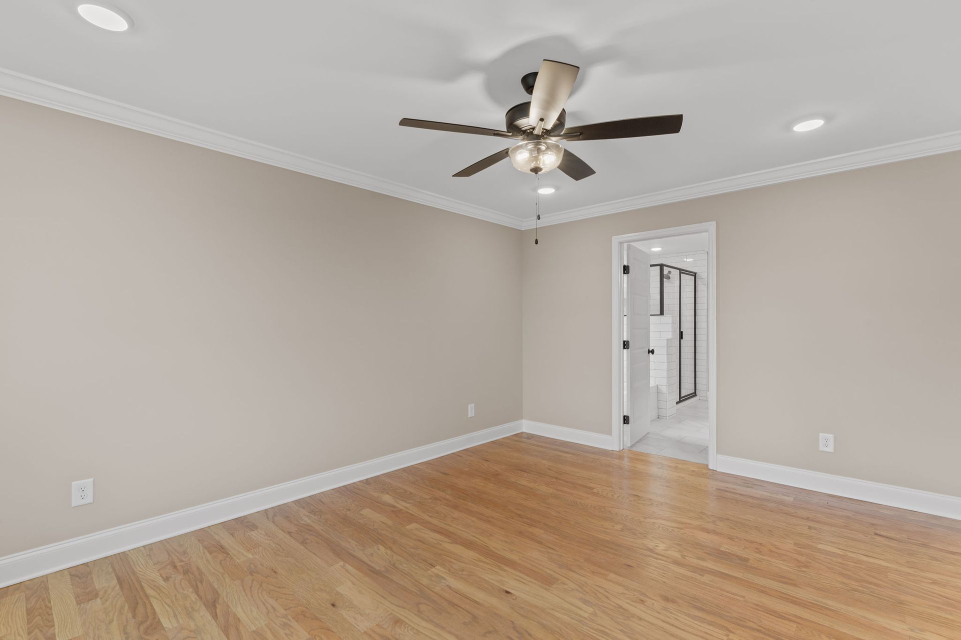 An empty room with hardwood floors and a ceiling fan.