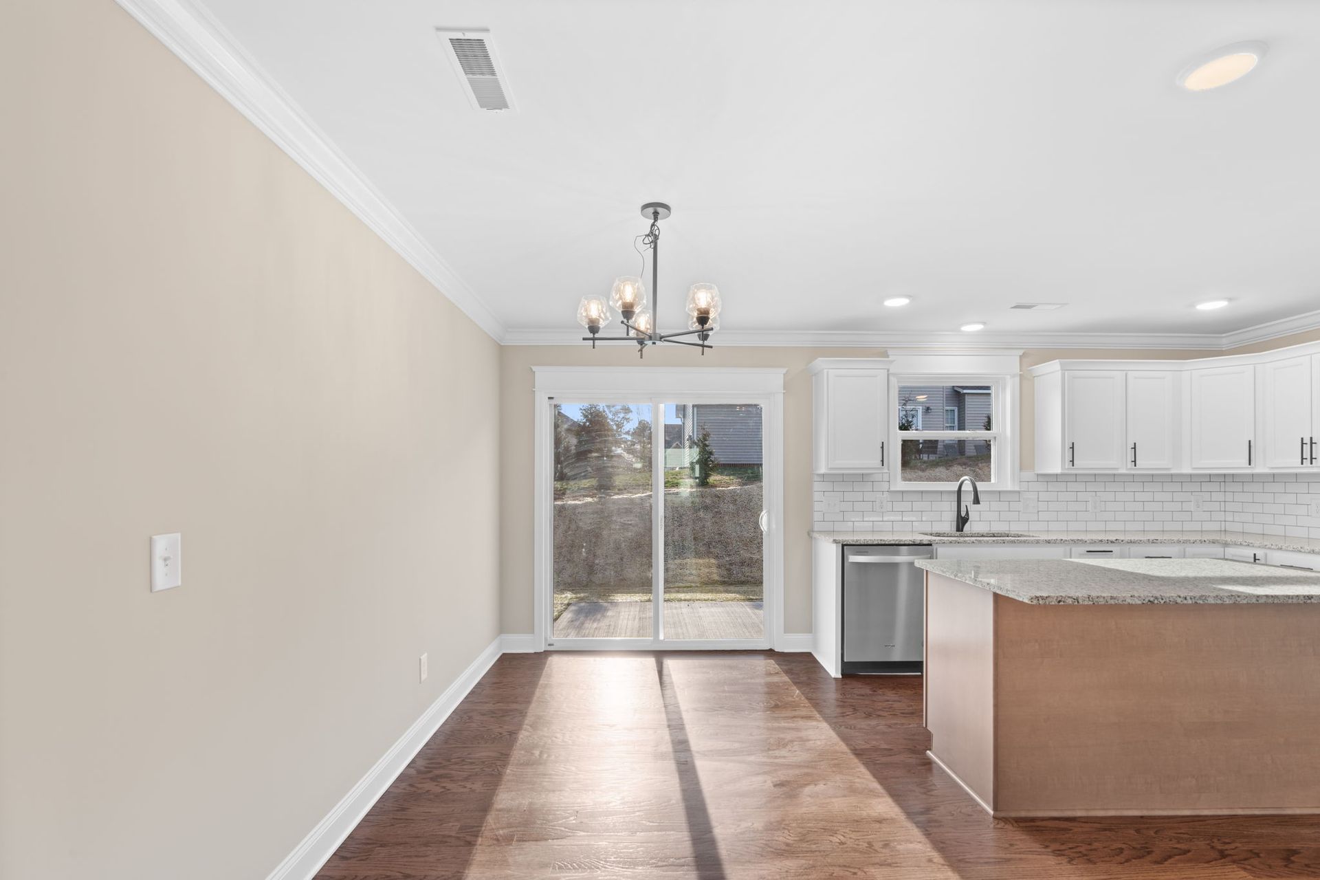 An empty kitchen with sliding glass doors and a chandelier hanging from the ceiling.