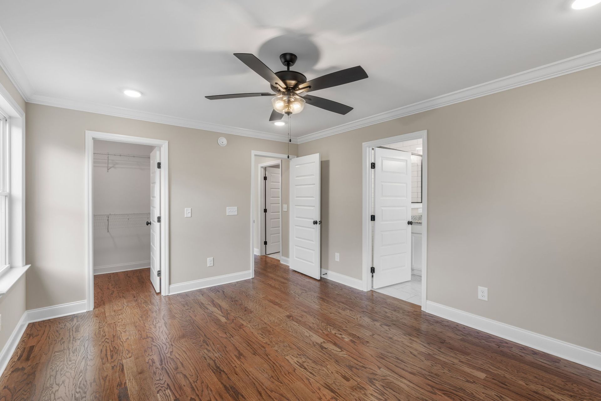 An empty room with hardwood floors and a ceiling fan.