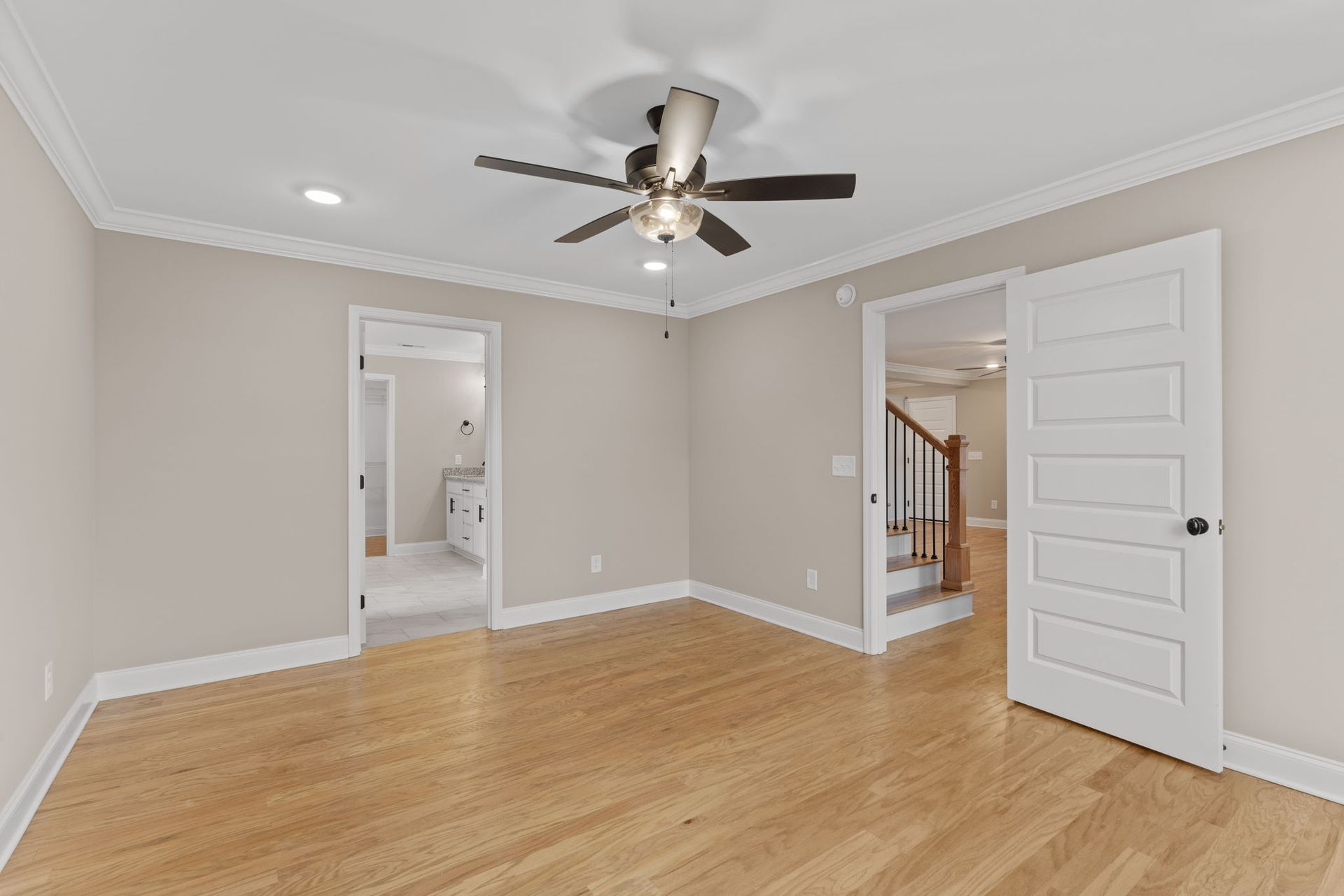 An empty room with hardwood floors and a ceiling fan.