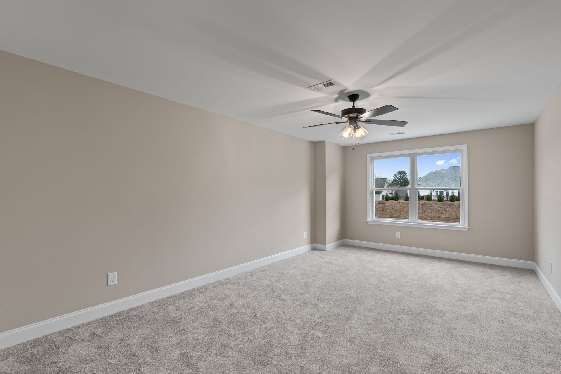 An empty bedroom with a ceiling fan and two windows.