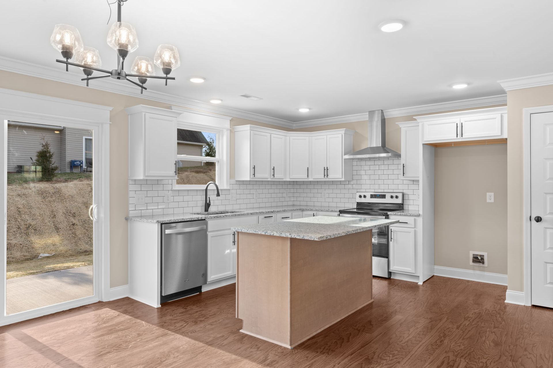 A kitchen with white cabinets , stainless steel appliances , hardwood floors and a large island.