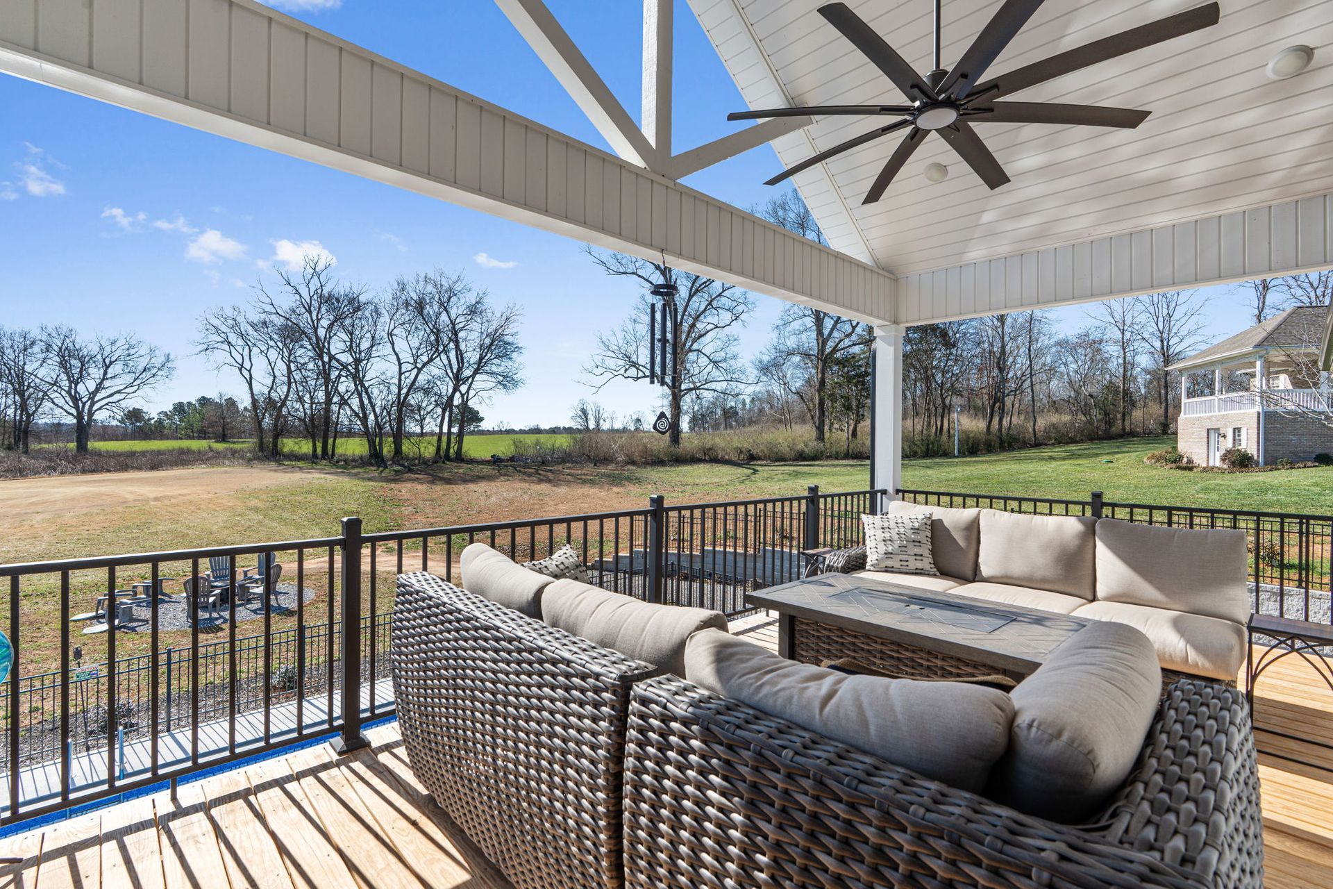 A patio with a couch , chairs , and a ceiling fan.