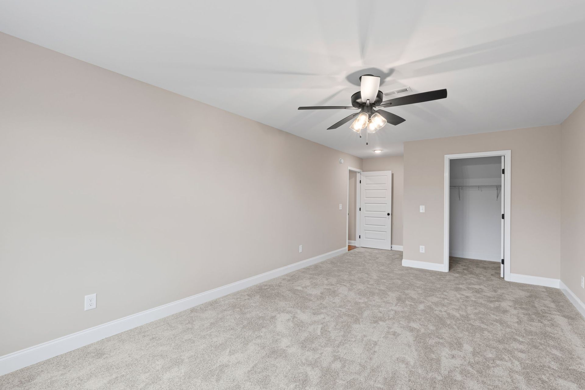 An empty bedroom with a ceiling fan and a closet.