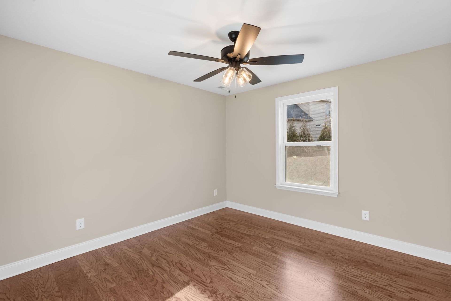 An empty room with a ceiling fan and a window.