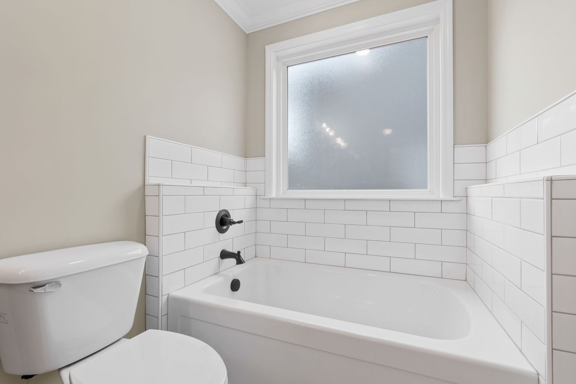 A bathroom with a toilet , tub and window.