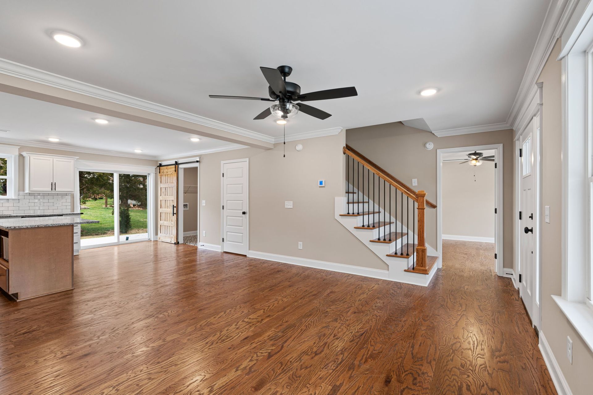 An empty living room with hardwood floors and a ceiling fan.