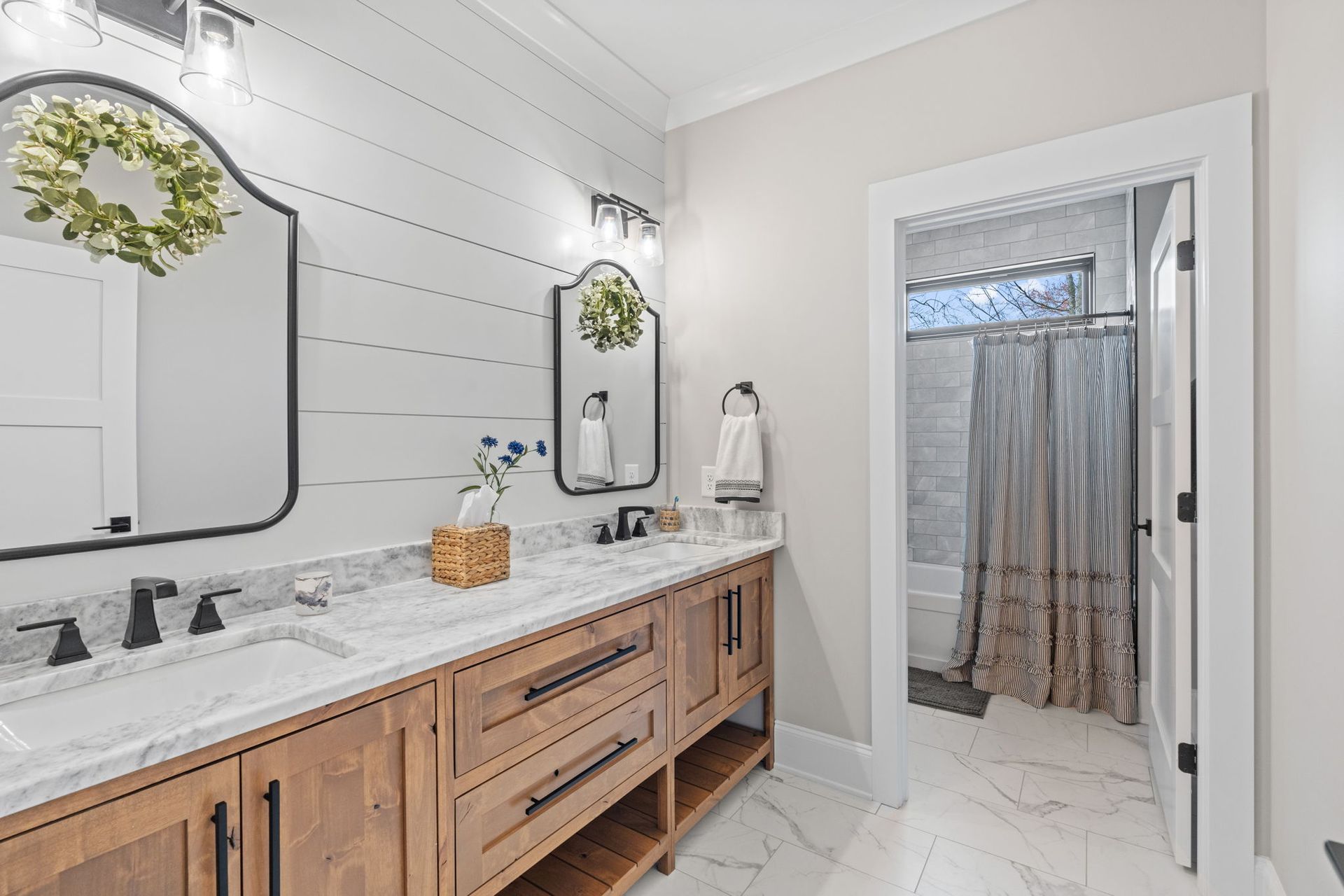A bathroom with two sinks , two mirrors and a shower curtain.