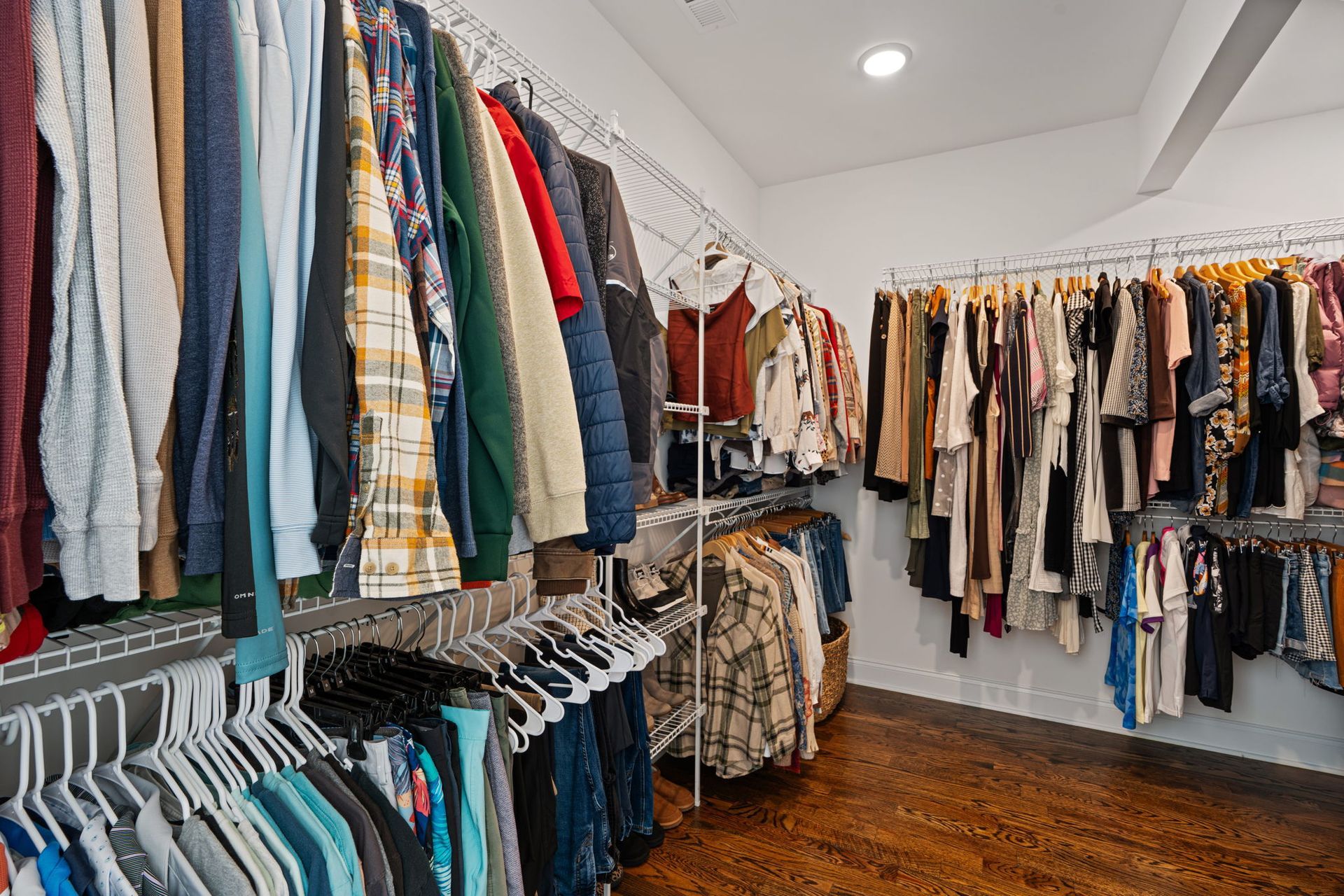 A closet filled with lots of clothes hanging on racks.