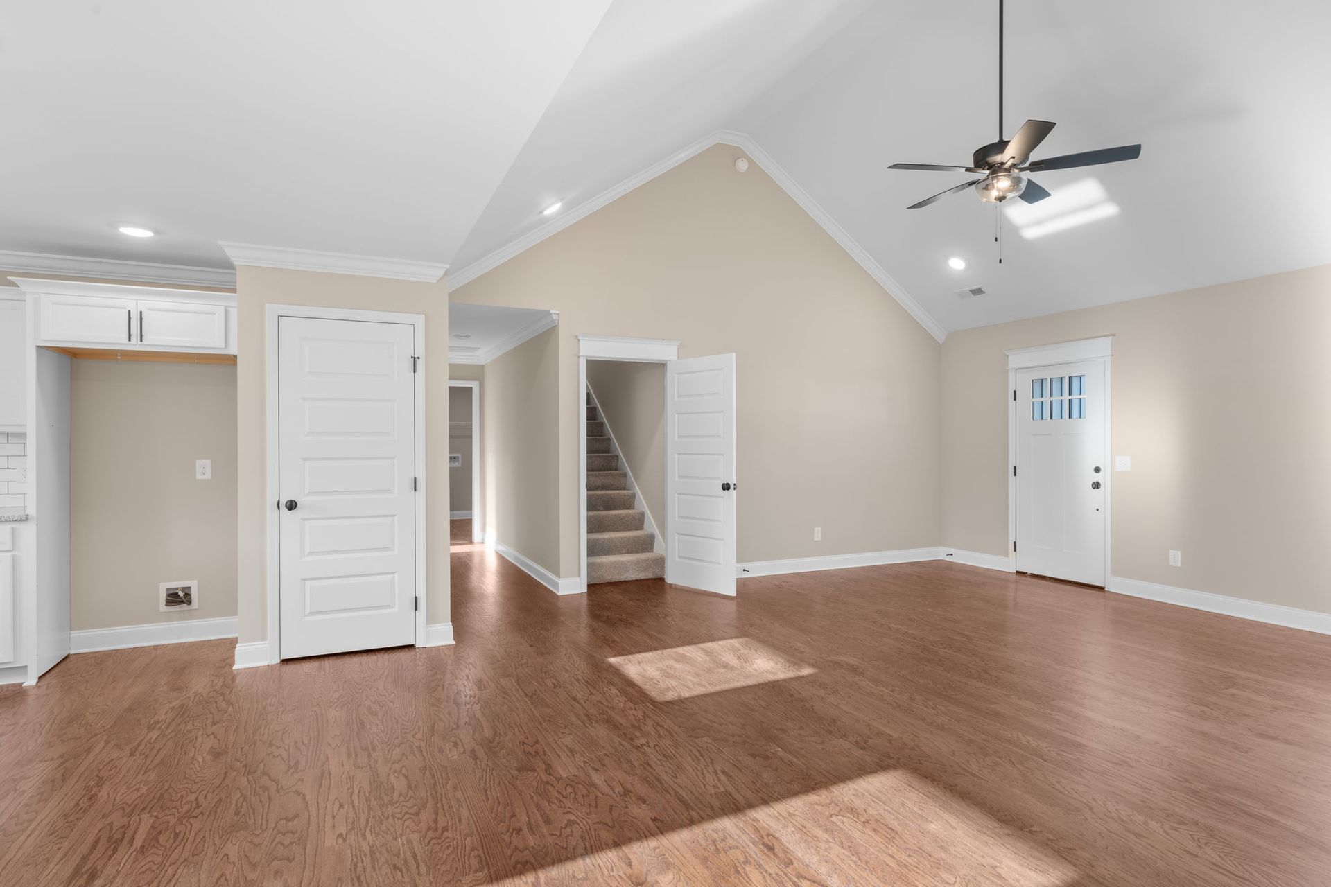 An empty living room with hardwood floors and a ceiling fan.