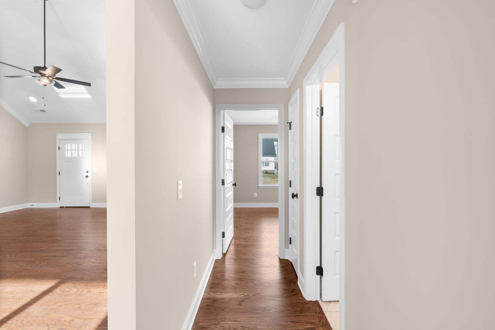 A hallway in a house with hardwood floors and a ceiling fan.
