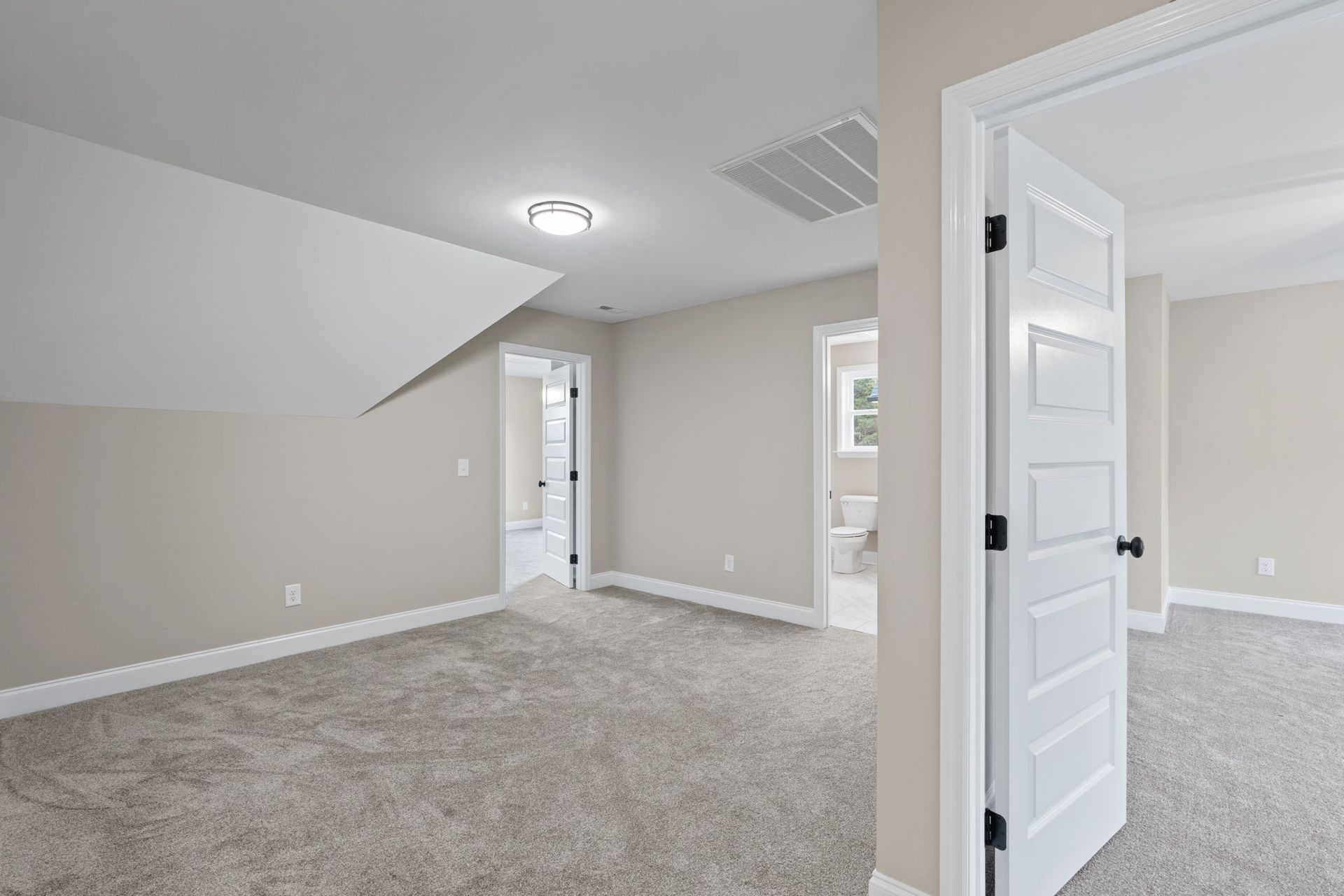 An empty room with a carpeted floor and a white door.