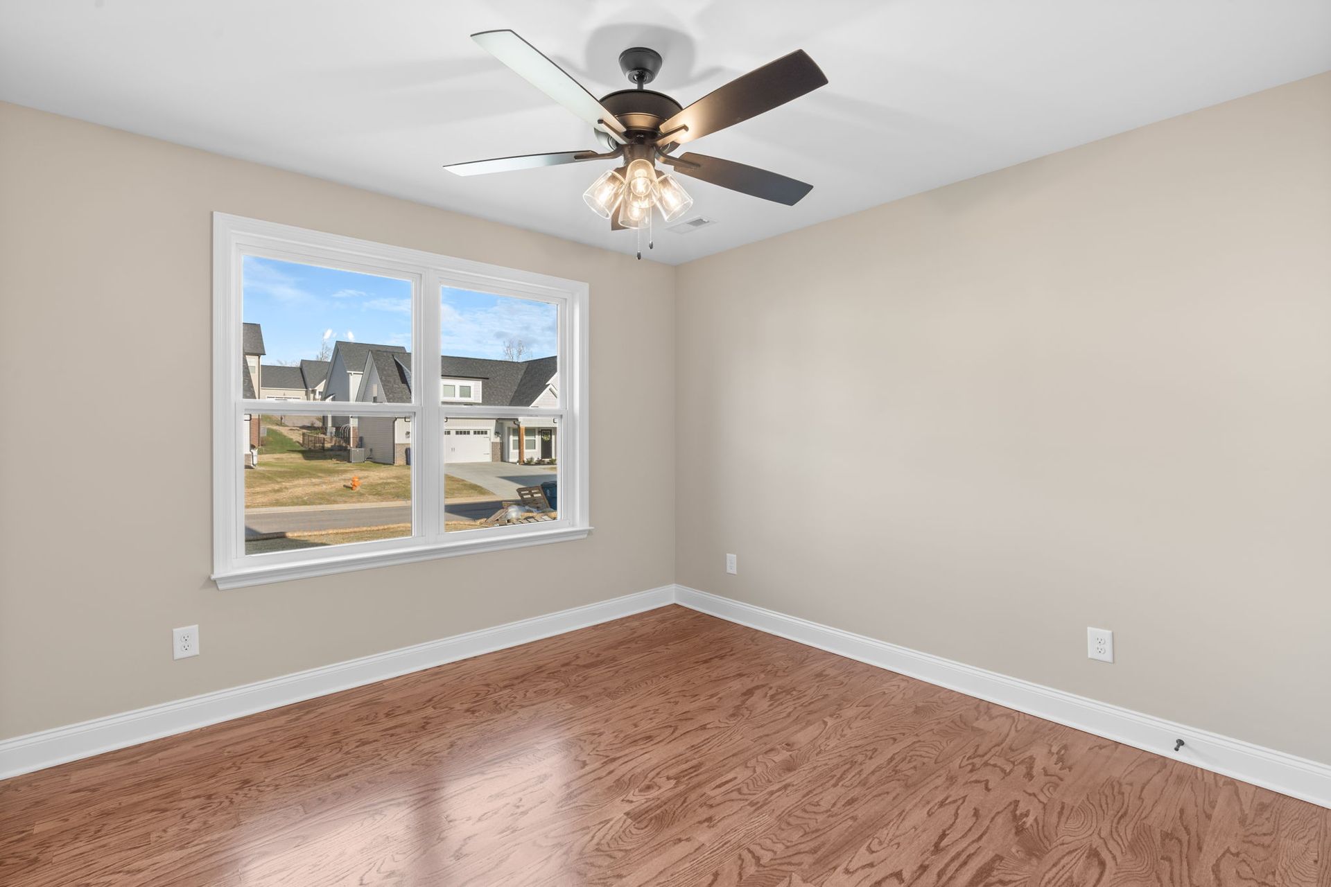 An empty room with hardwood floors and a ceiling fan.
