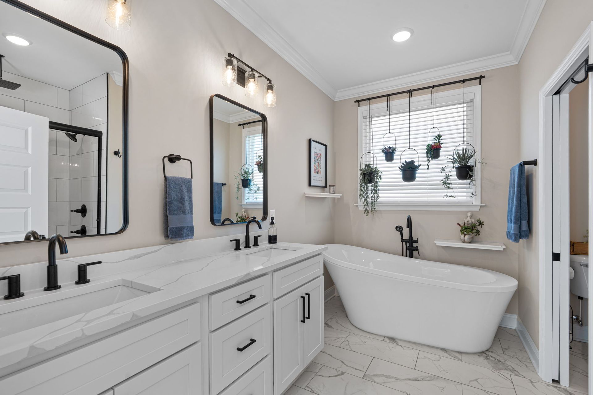 A bathroom with two sinks , a tub , and two mirrors.