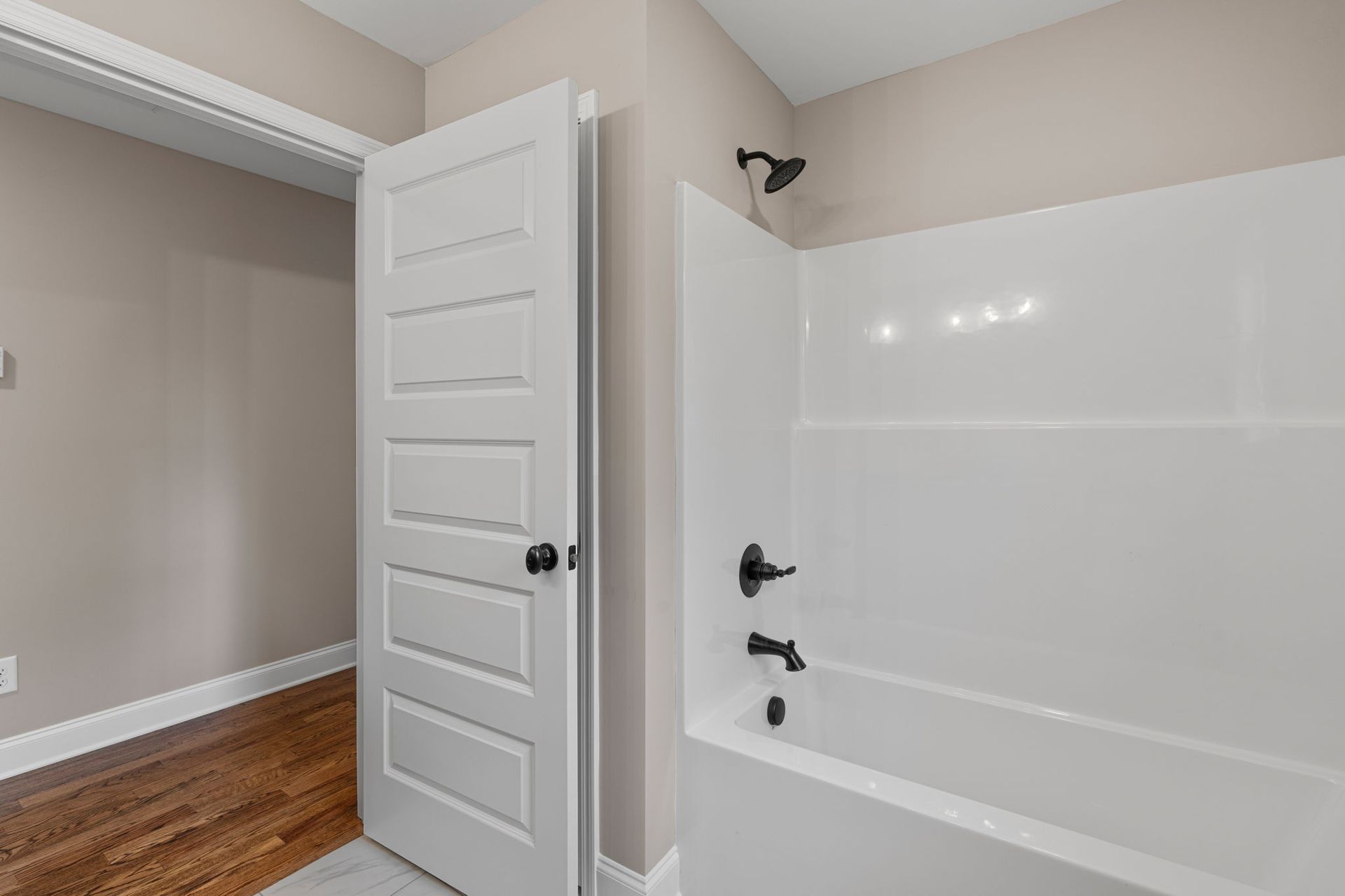 A bathroom with a tub , shower , and door.