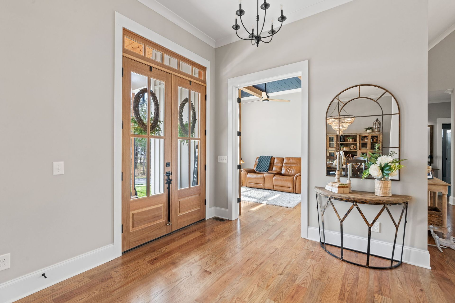 A hallway in a house with hardwood floors and a mirror.
