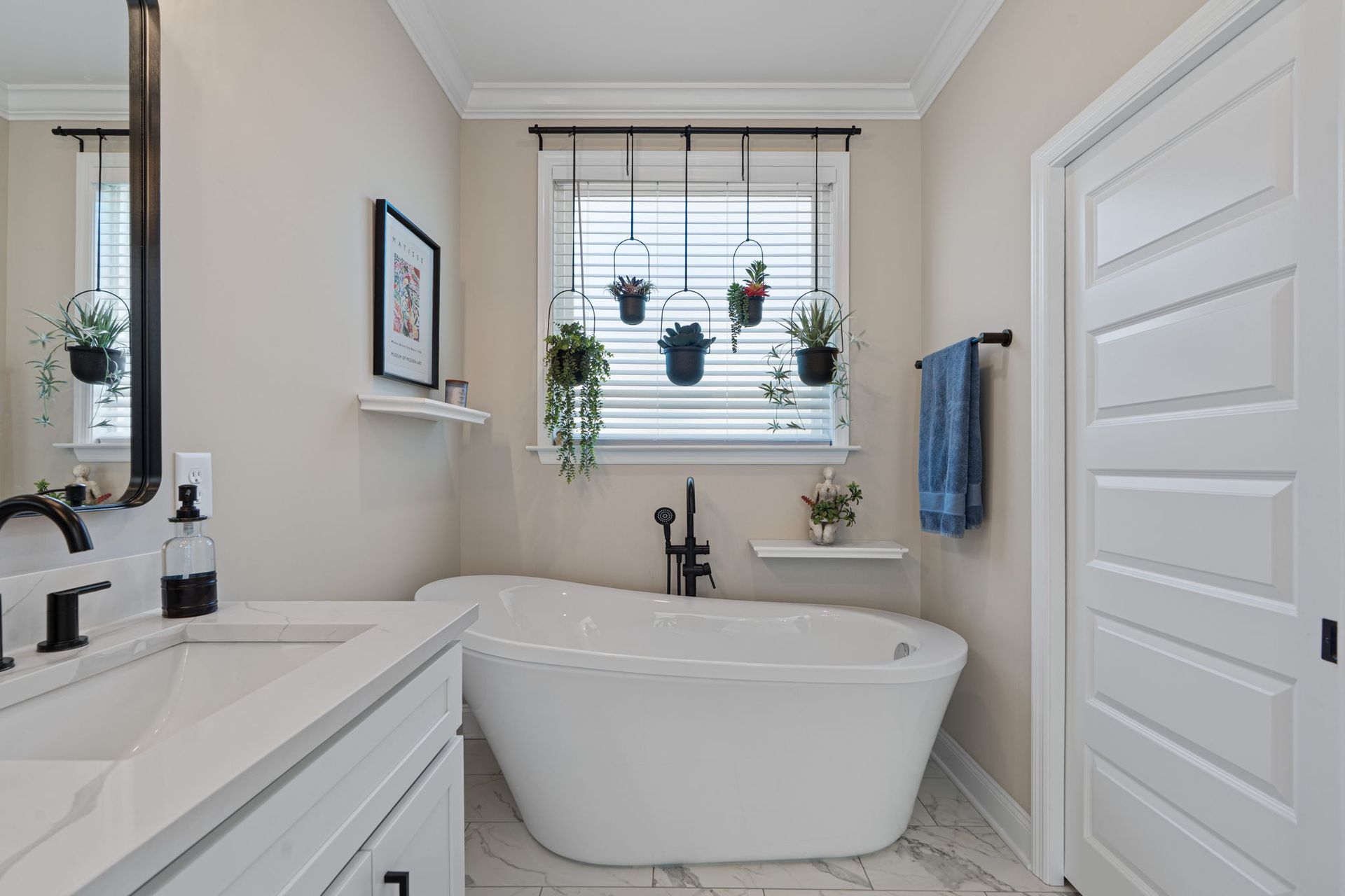 A bathroom with a tub , sink , mirror and window.
