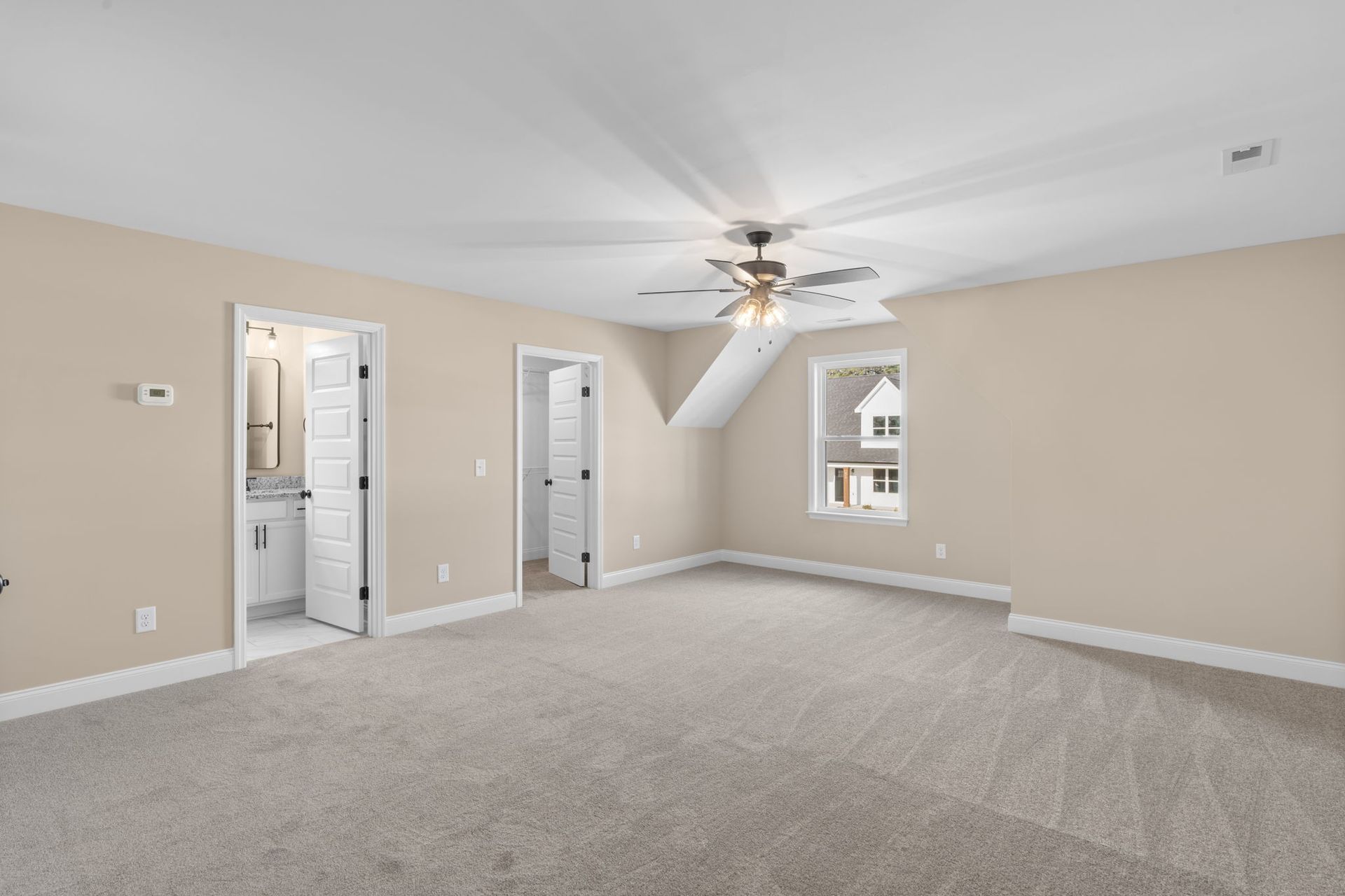 An empty bedroom with a ceiling fan and a bathroom.