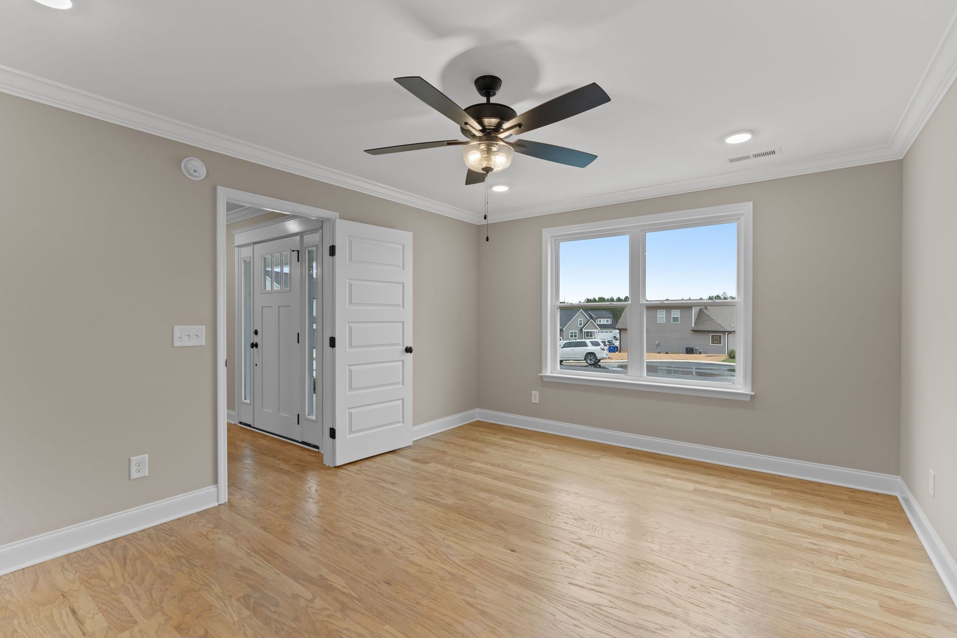 An empty bedroom with hardwood floors and a ceiling fan.