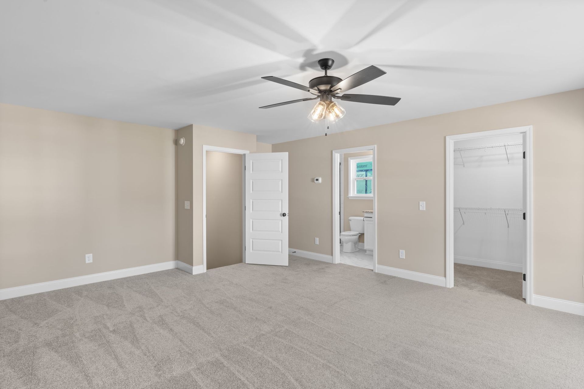 An empty bedroom with a ceiling fan and a walk in closet.