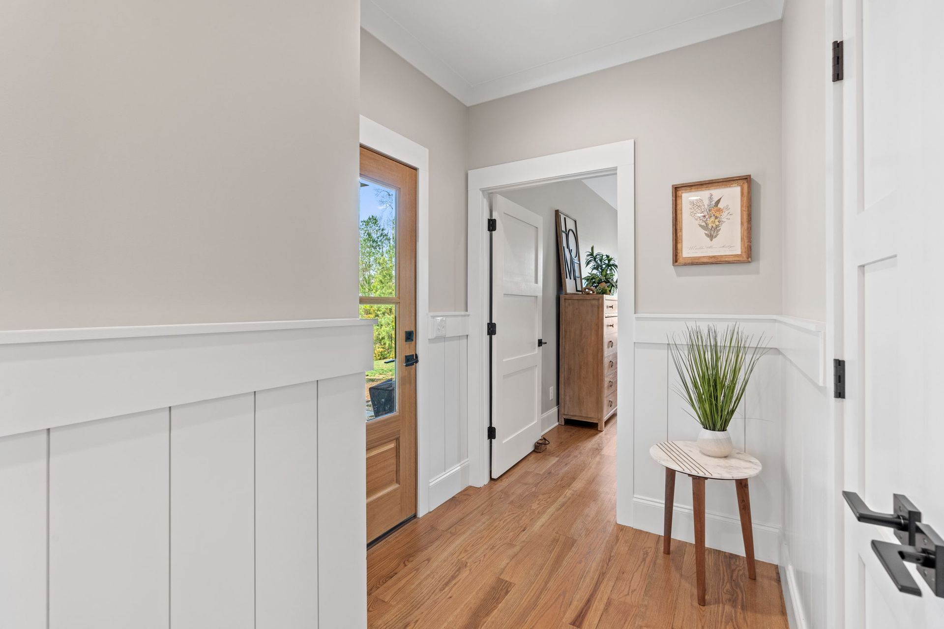 A hallway in a house with hardwood floors and white trim.