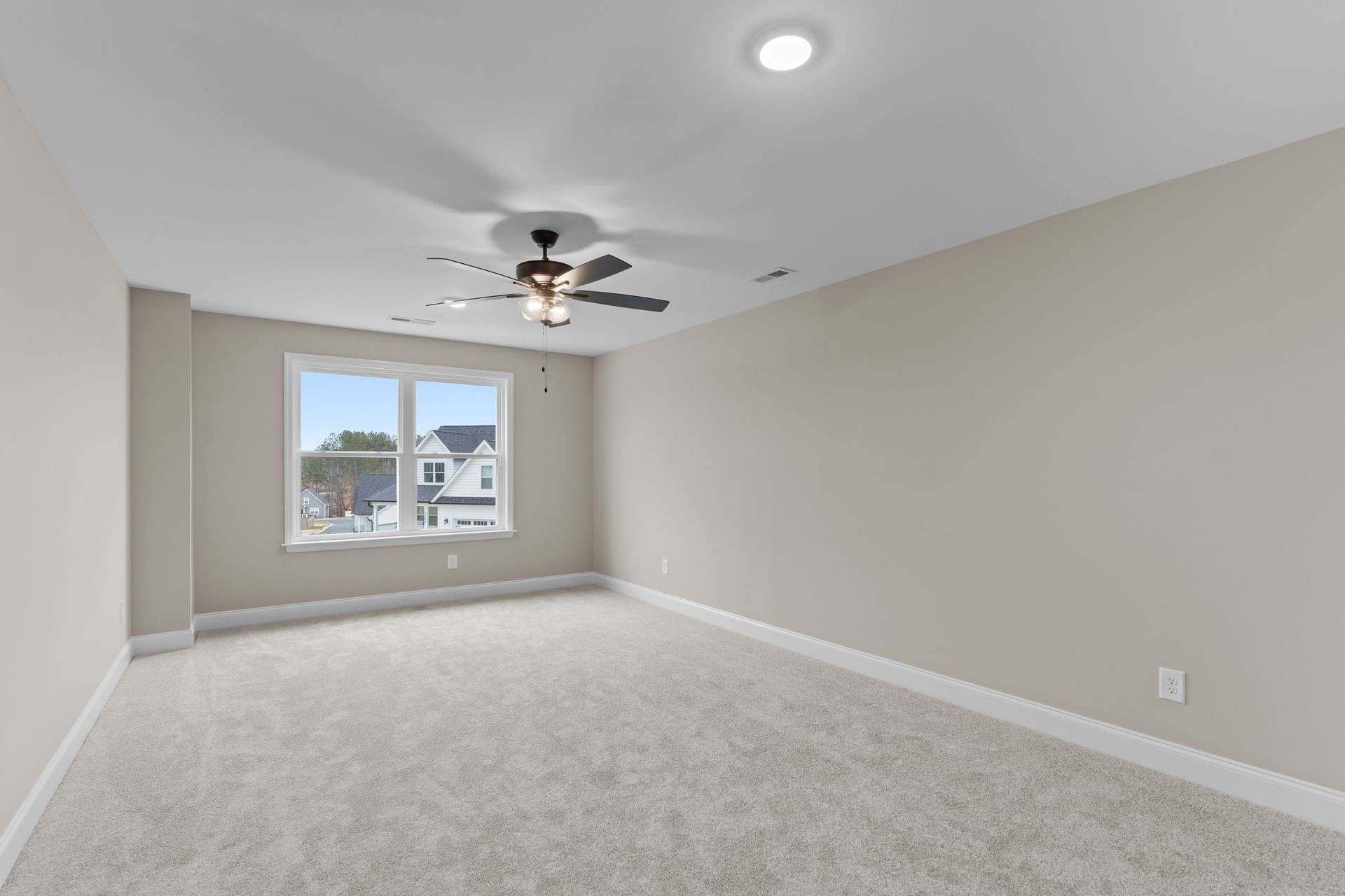 An empty bedroom with a ceiling fan and a window.
