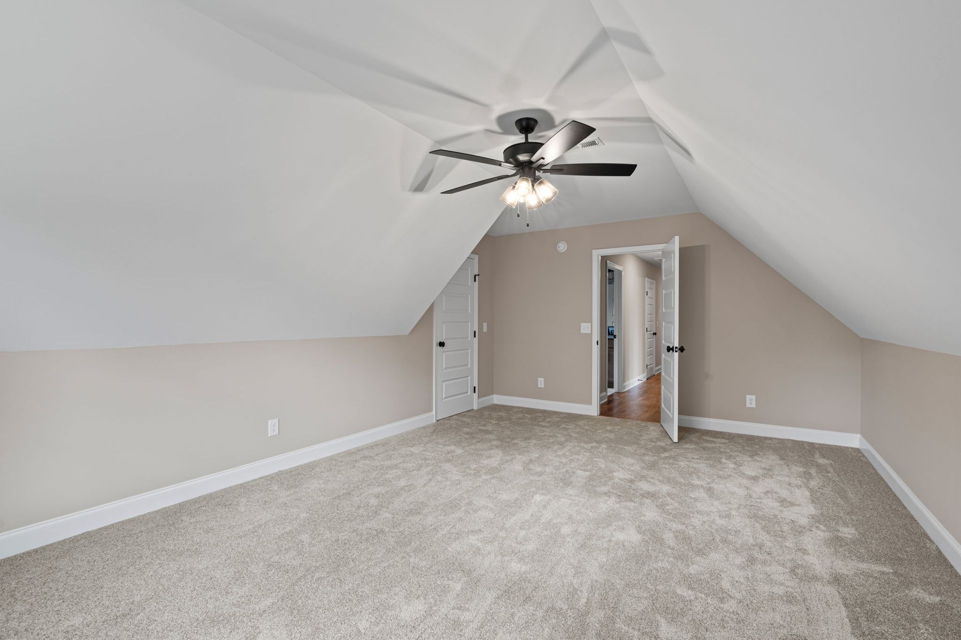 An empty bedroom with a ceiling fan and a carpeted floor.