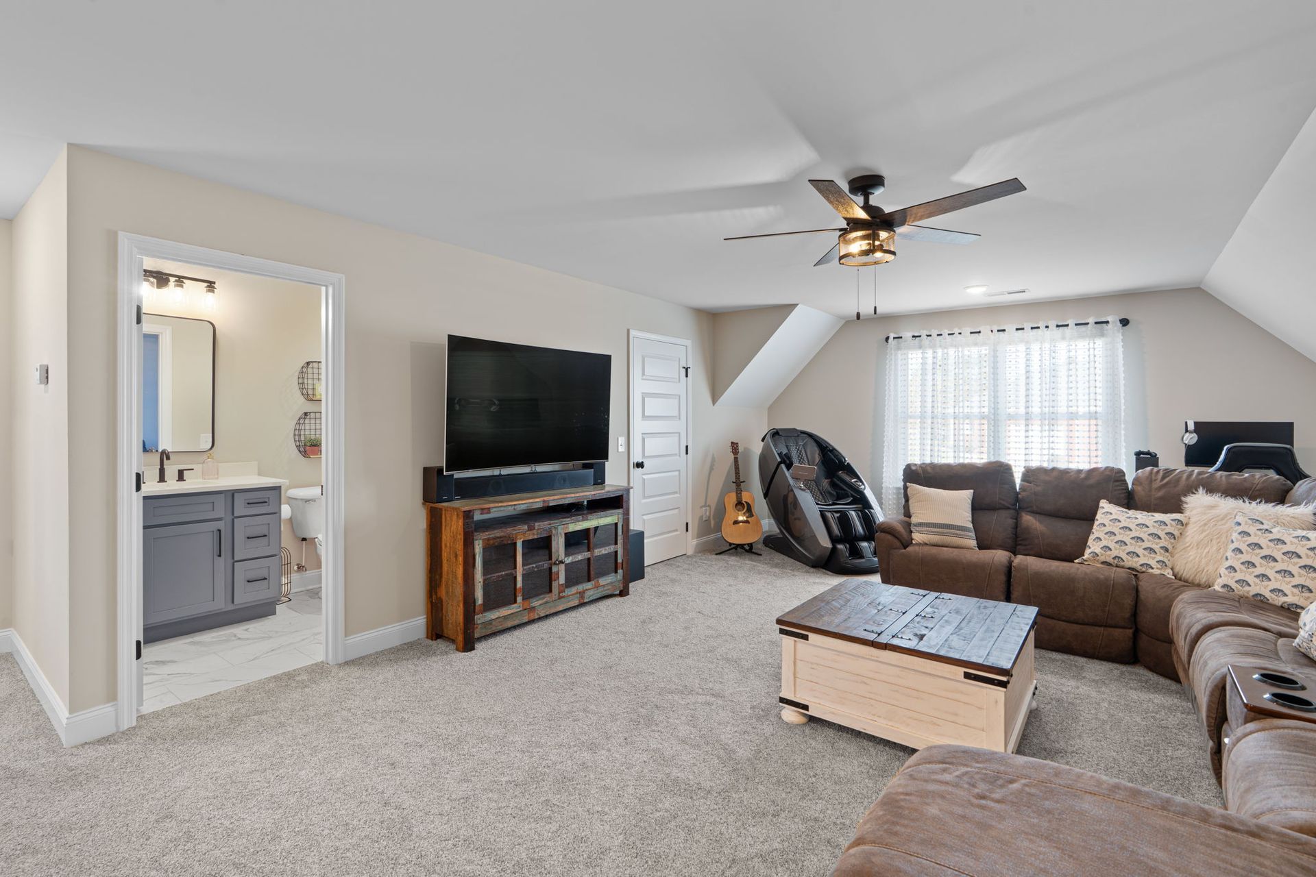 A living room with a couch , table , television and ceiling fan.