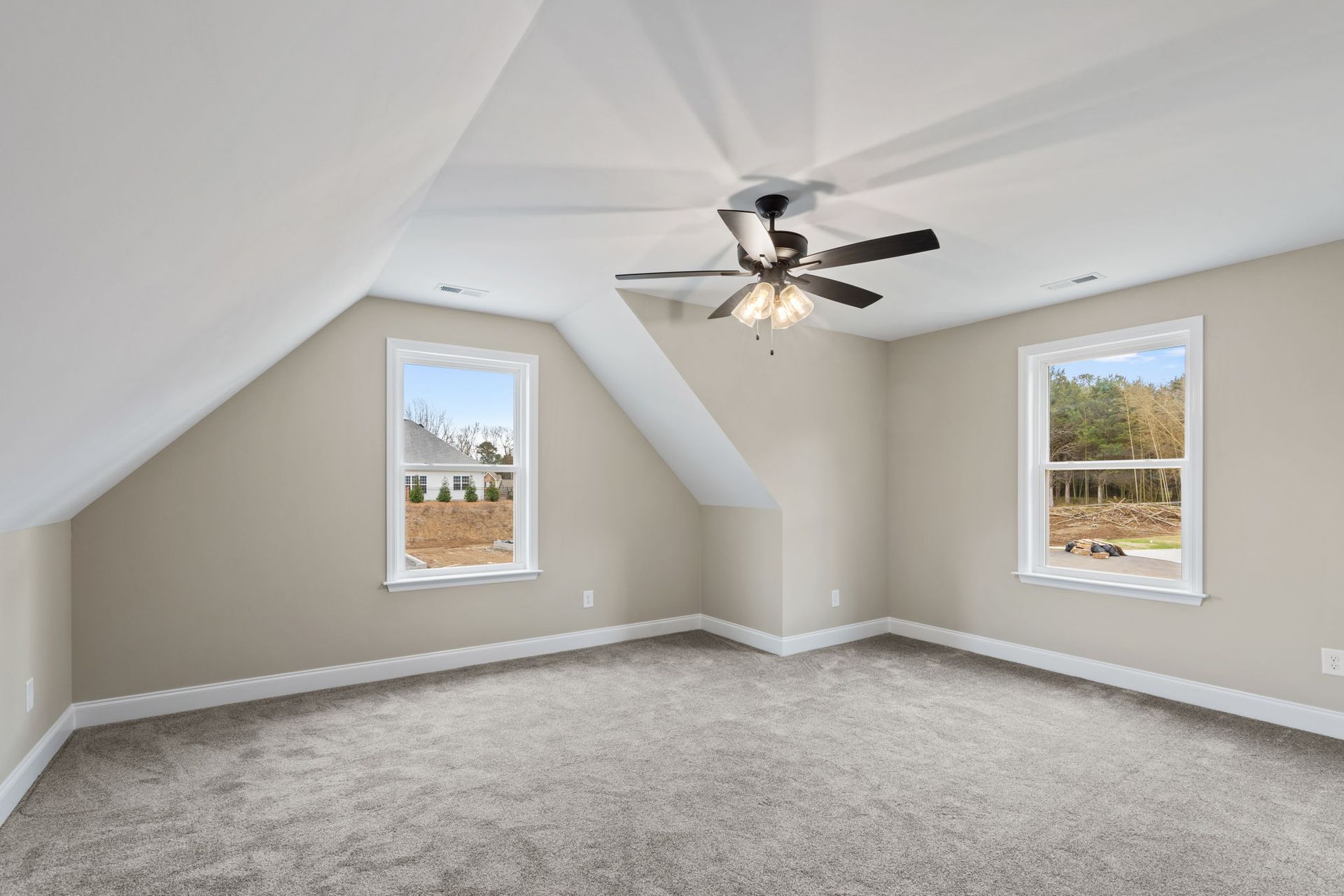 An empty bedroom with a ceiling fan and two windows.