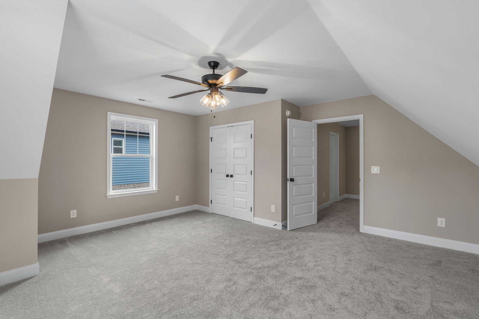 An empty bedroom with a ceiling fan and a window.