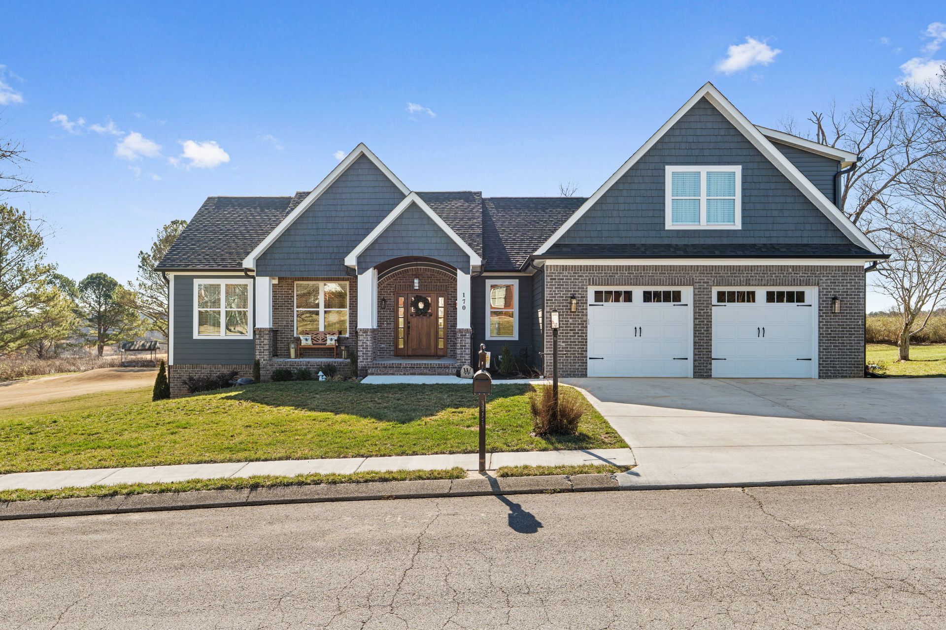 A large brick house with a gray siding and white garage doors