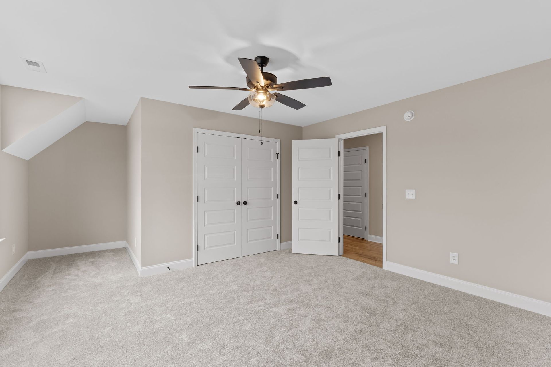 An empty bedroom with a ceiling fan and a closet.