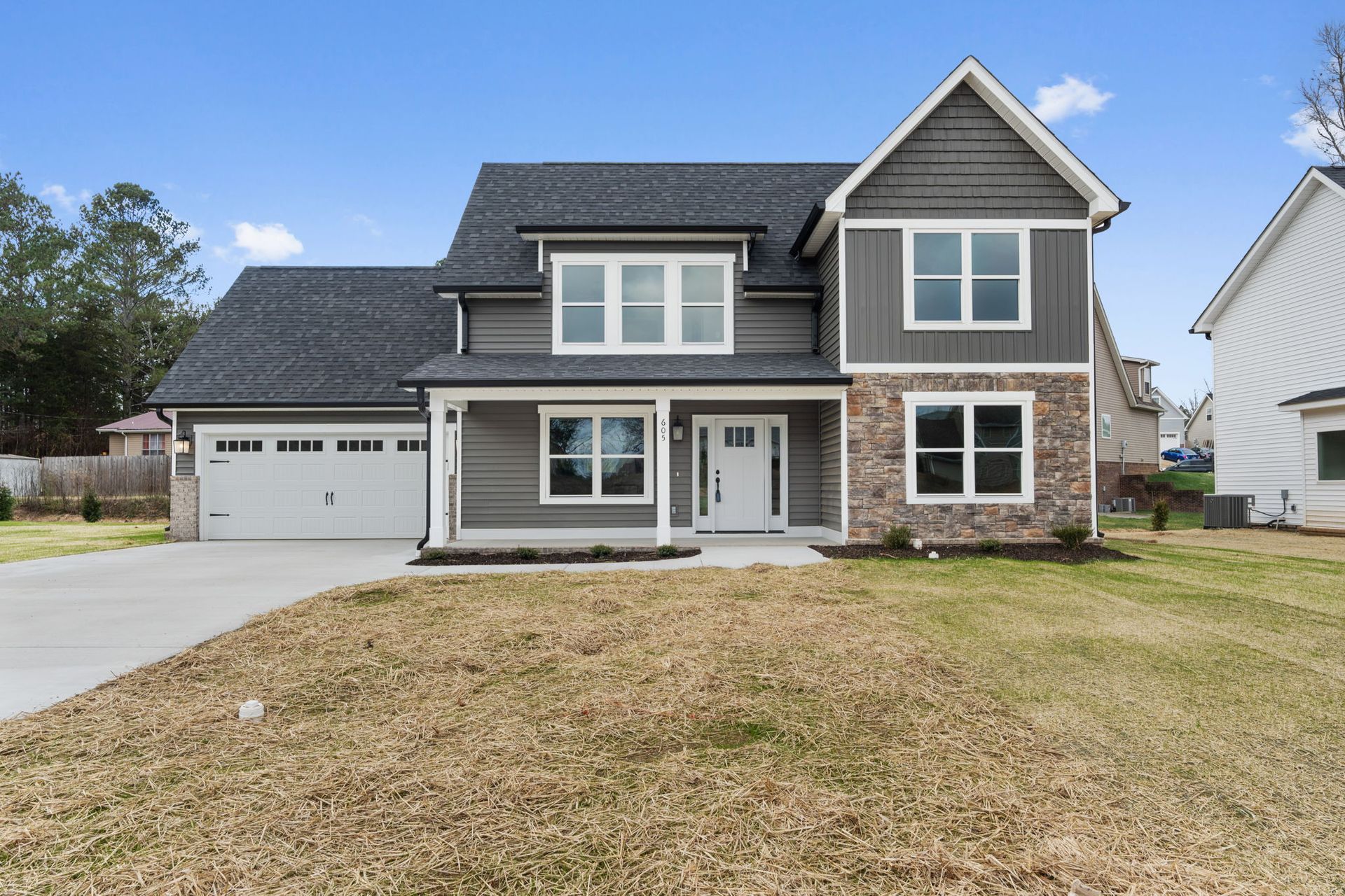A large house with a gray siding and a white garage door is for sale.