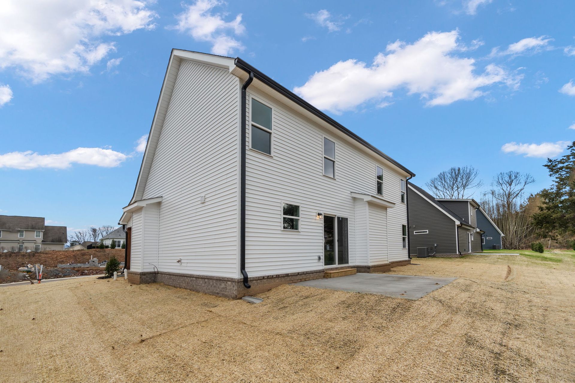 A white house with a lot of windows is sitting on top of a dirt field.