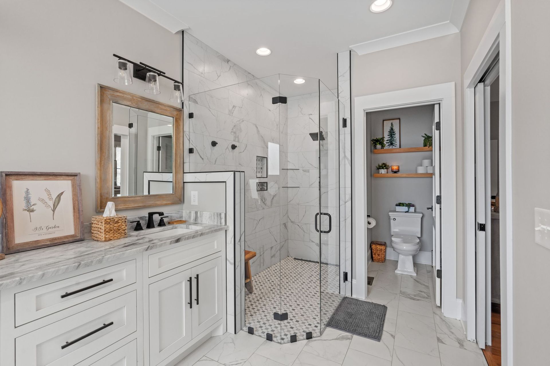 A bathroom with a walk in shower , sink , toilet and mirror.