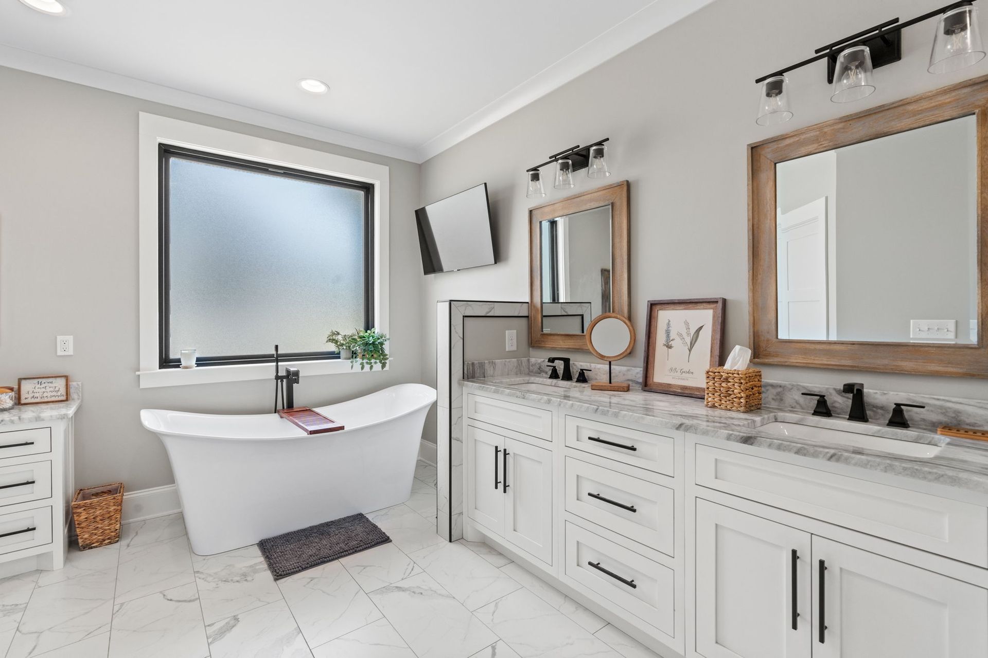 A bathroom with a tub , sinks , mirrors and a window.