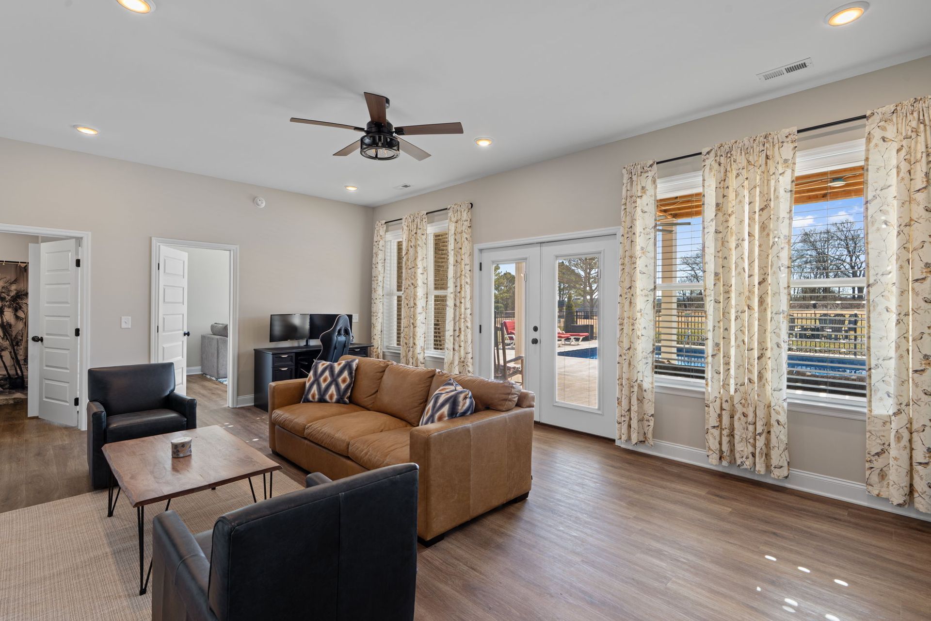 A living room with a couch , chairs , and a ceiling fan.