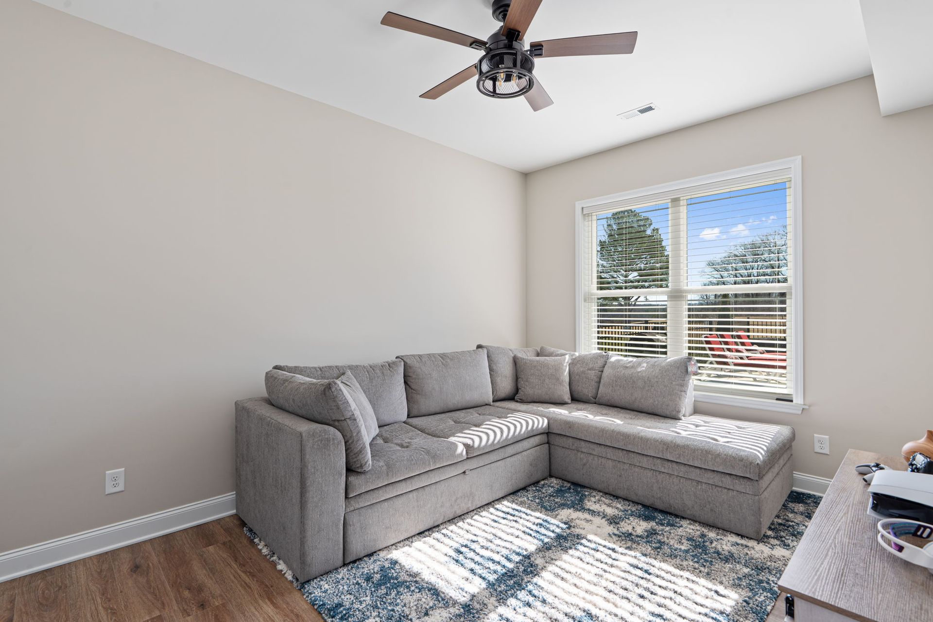 A living room with a sectional couch and a ceiling fan.