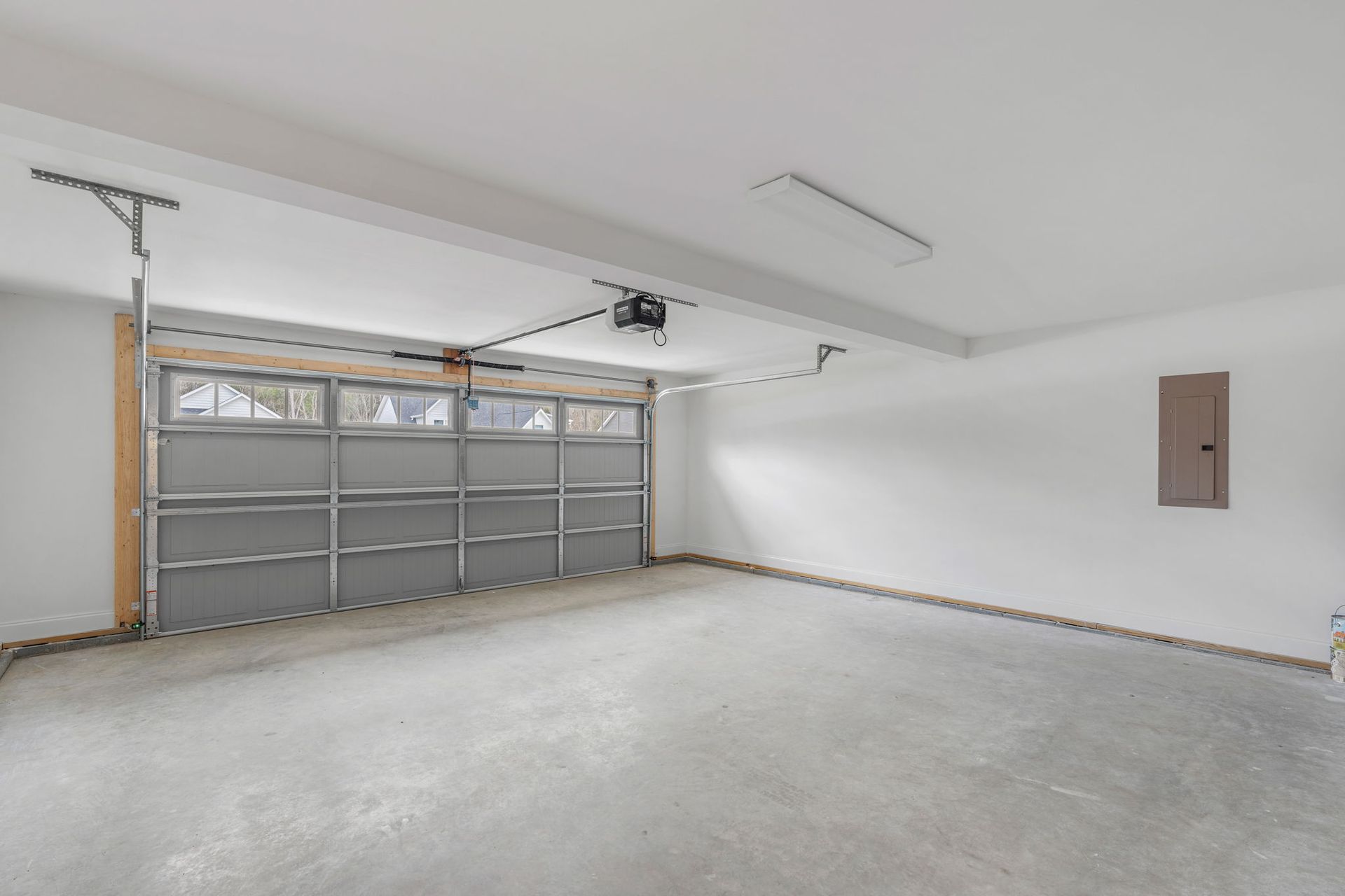 An empty garage with a garage door open and a ceiling fan.