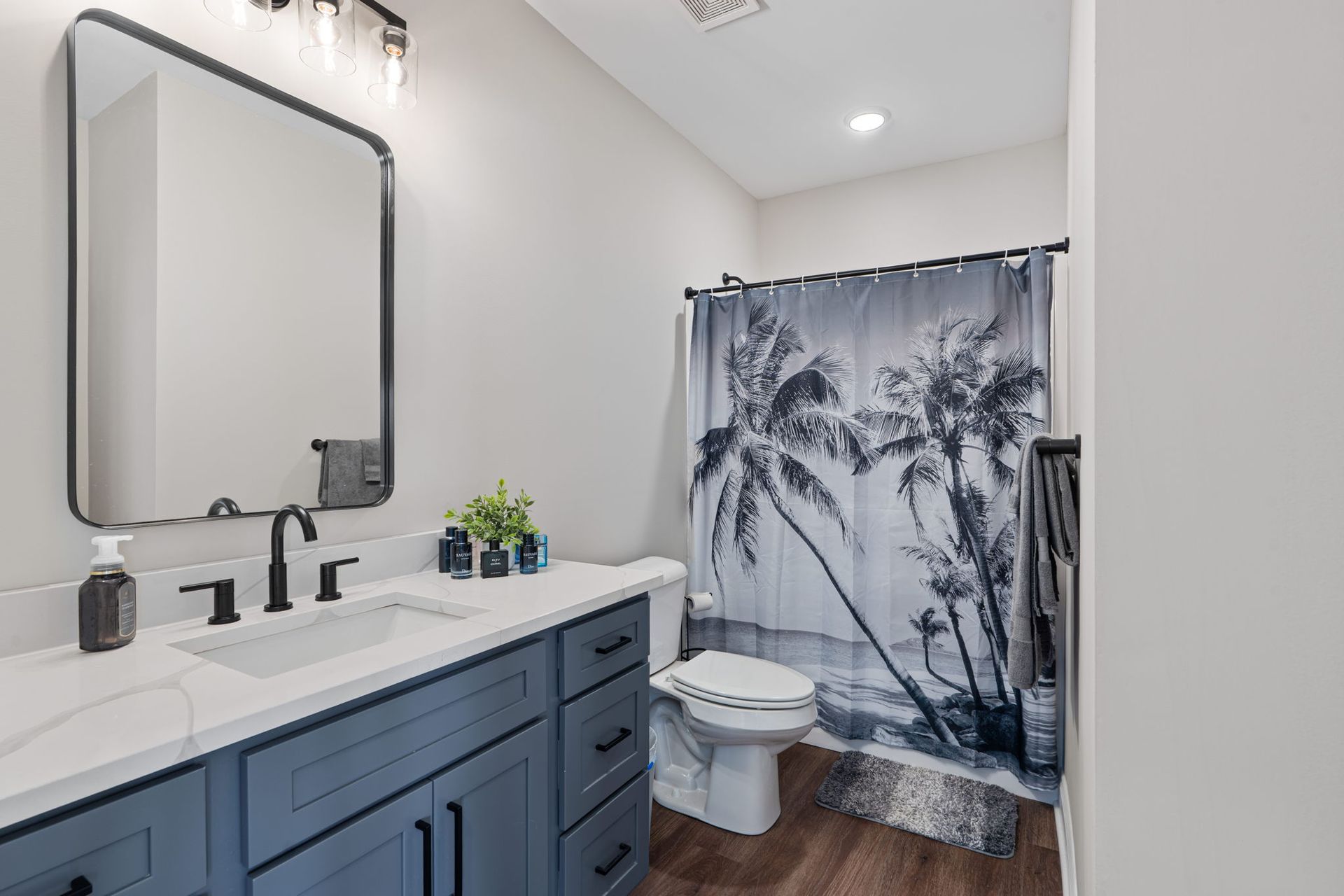 A bathroom with a sink , toilet , shower curtain and mirror.