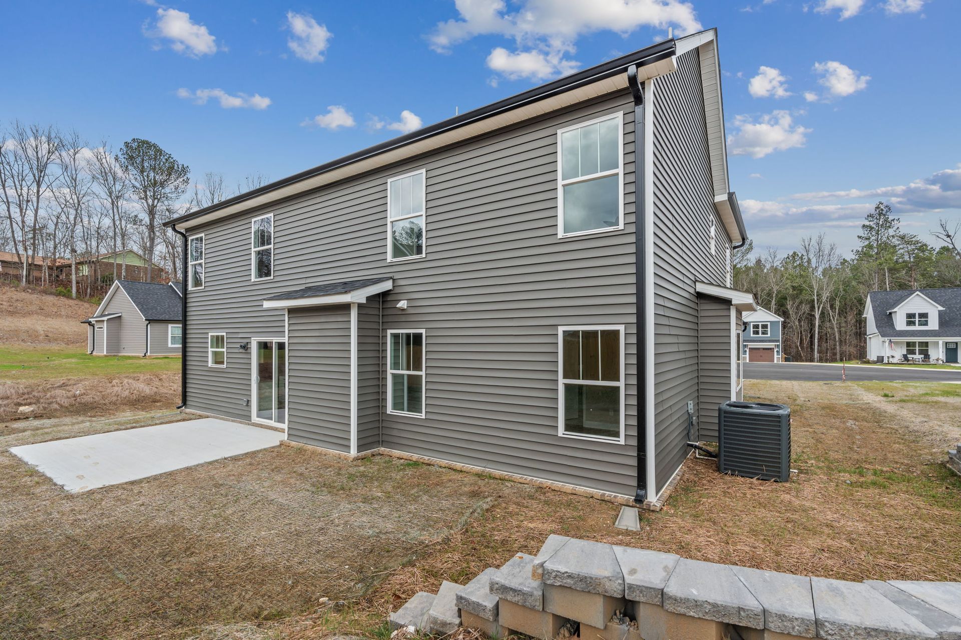 The back of a house with a lot of windows and a patio.