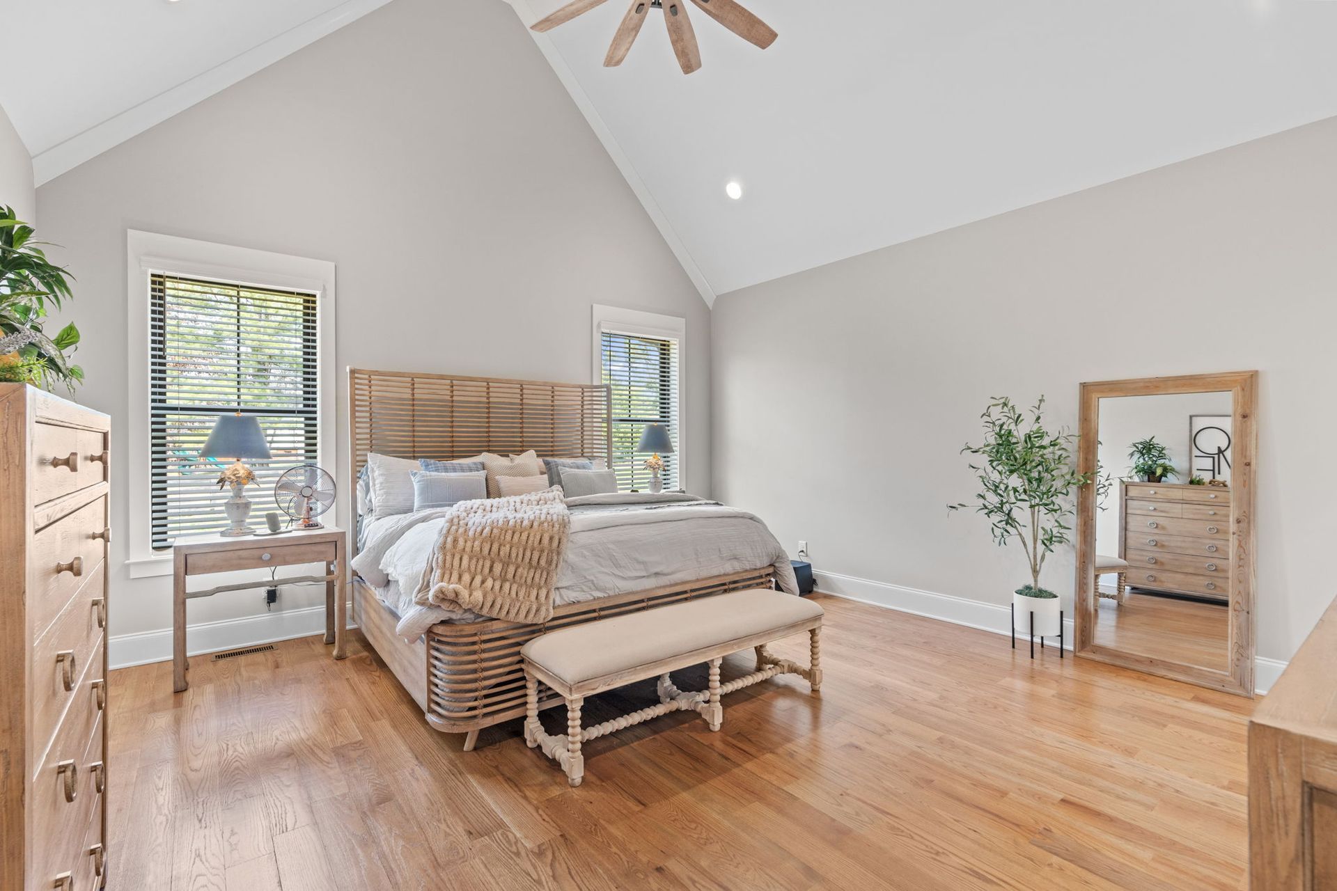 A bedroom with a bed , dresser , mirror and bench.