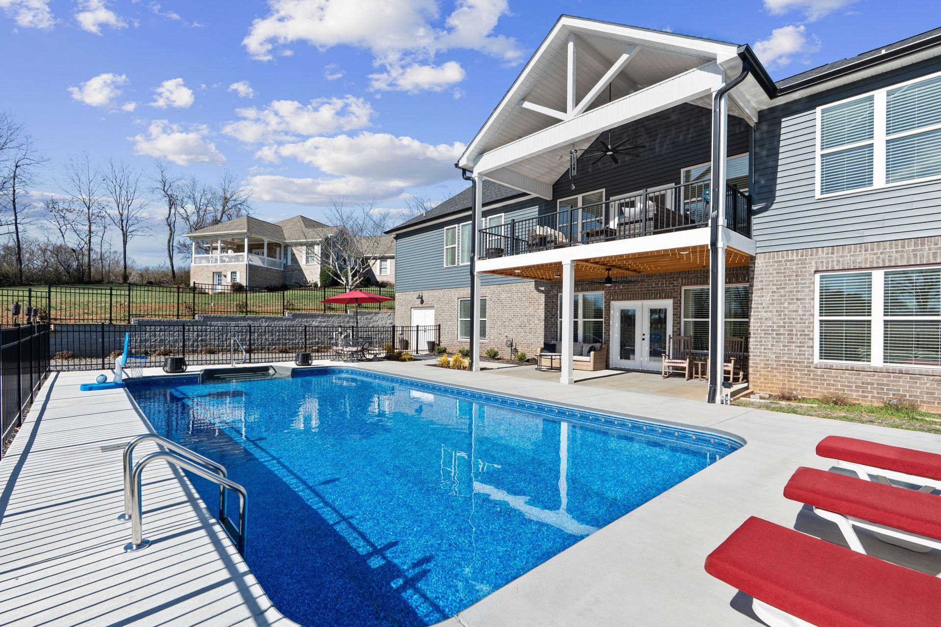 A large swimming pool is in front of a large house.