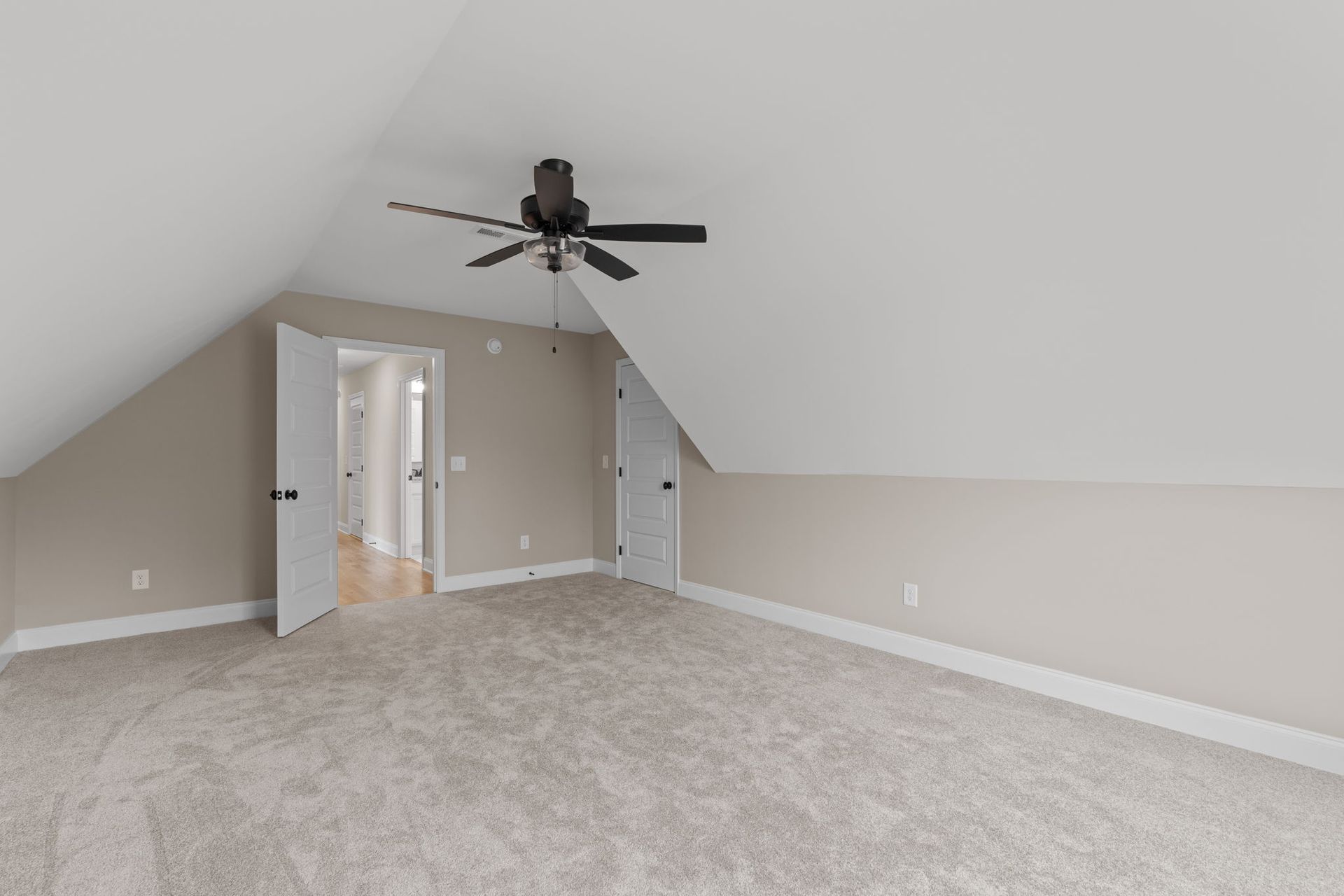 An empty bedroom with a ceiling fan and a vaulted ceiling.