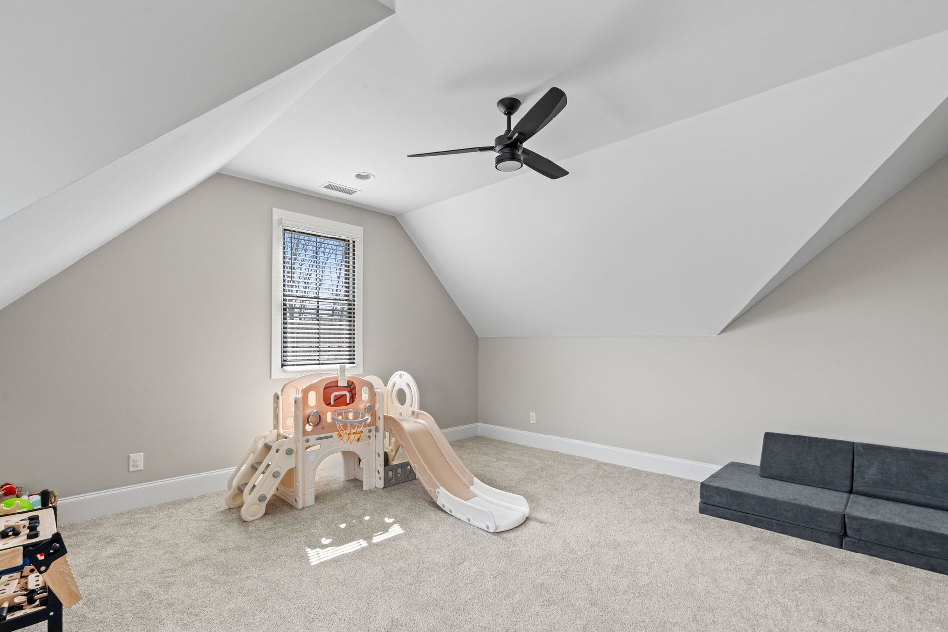 A room with a slide and a ceiling fan in it.
