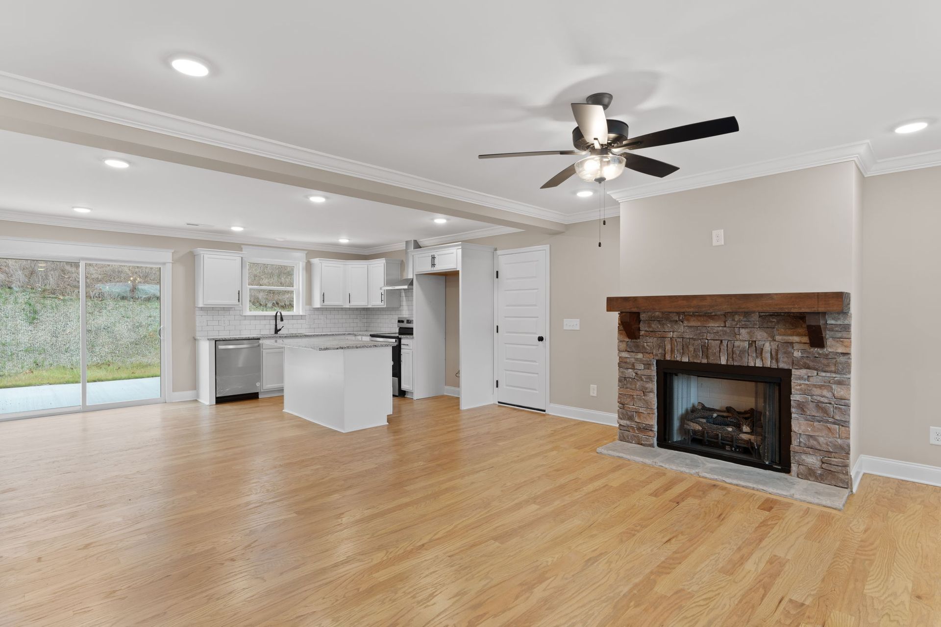 A living room with hardwood floors , a fireplace and a ceiling fan.